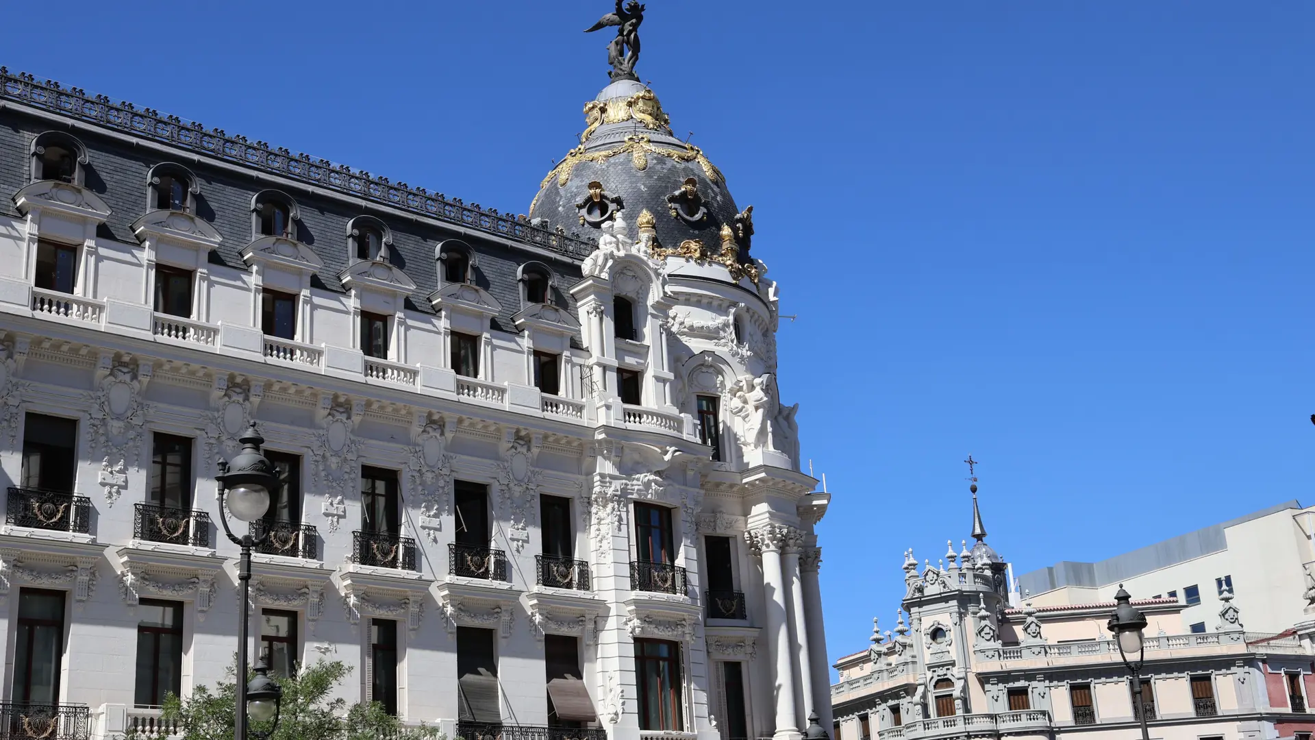 The ornate Metrópolis building and dark dome with gold bands at Calle de Alcalá in sunny Madrid.
