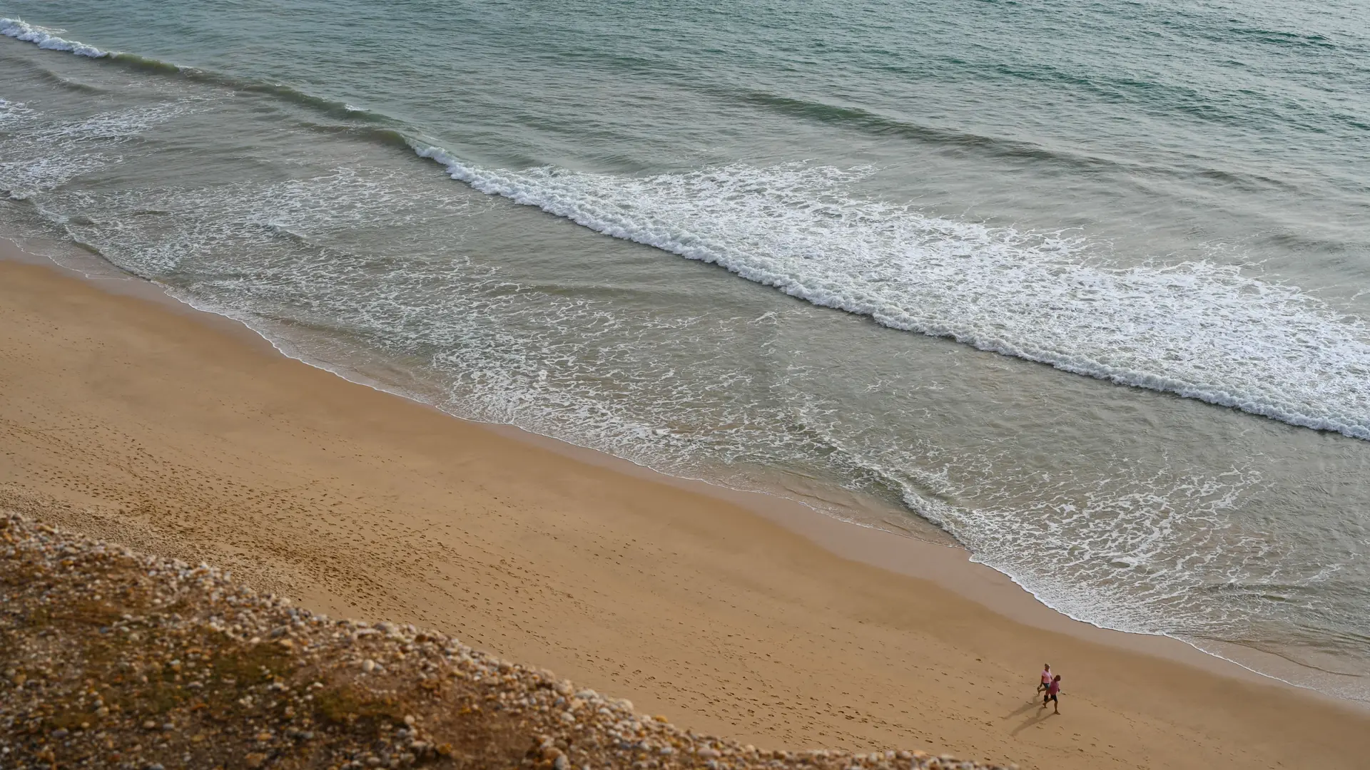 Wide Praia de Faro beach with golden sand, Atlantic surf and blue sky