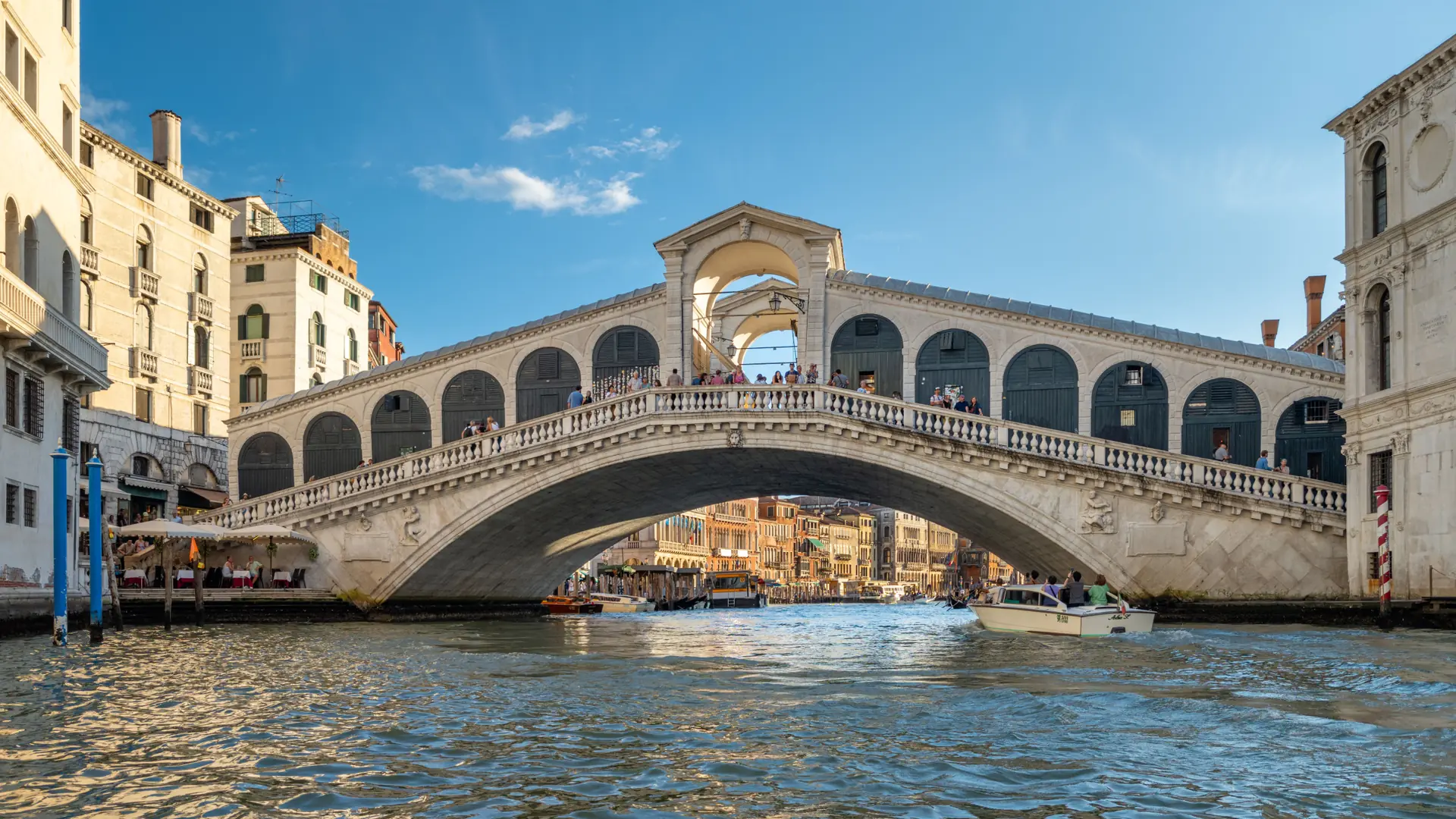 Rialto Bridge spanning the Grand Canal in Venice under a clear blue daytime sky