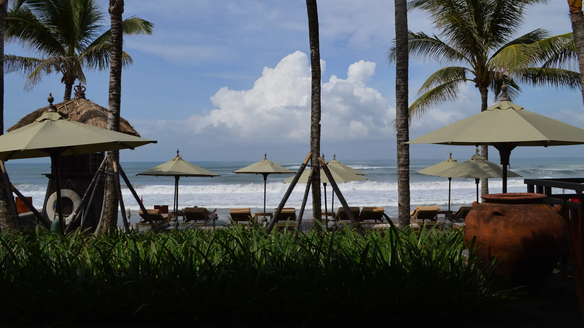 Palms and shaded loungers facing the sea at The Legian hotel in Seminyak
