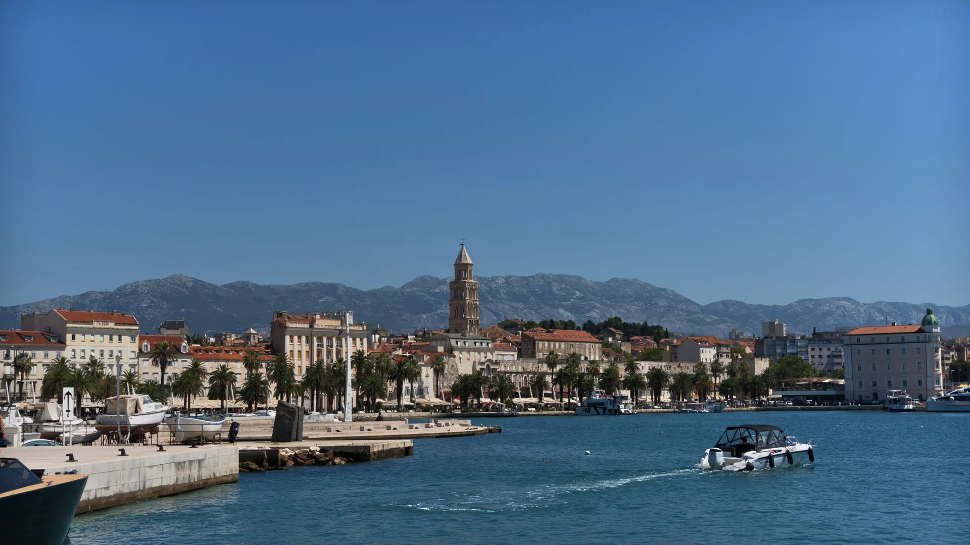 Split’s Riva waterfront and cathedral bell tower seen across the harbour in daylight.