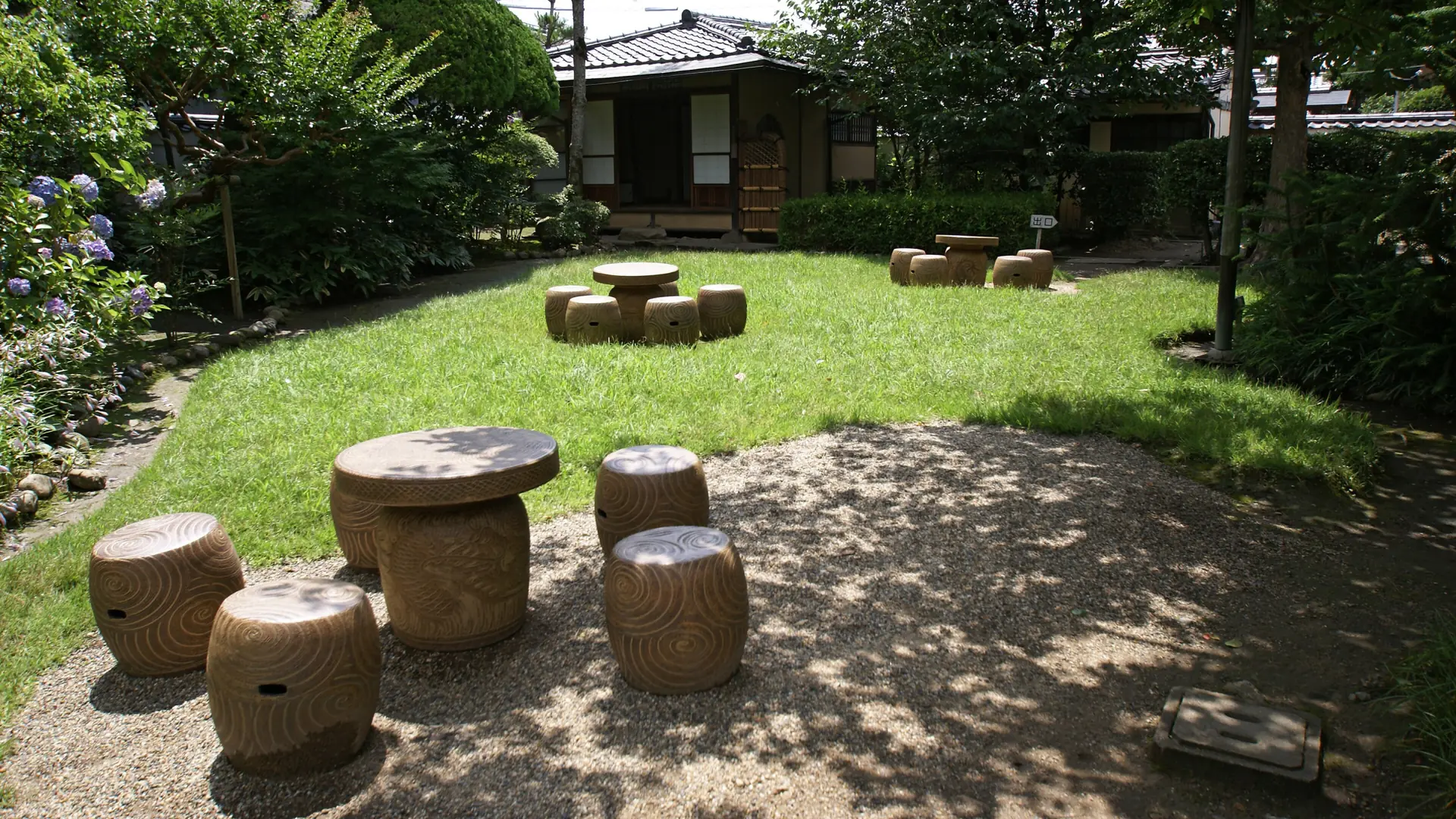 Sunlit lawn and round tables in the garden of Naoya Shiga’s former house in Nara