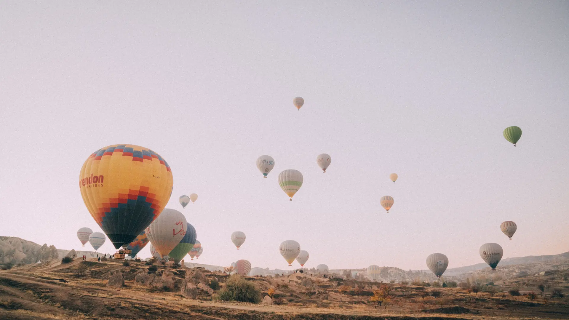 Hot-air balloons floating above Cappadocia's fairy chimneys in soft morning light