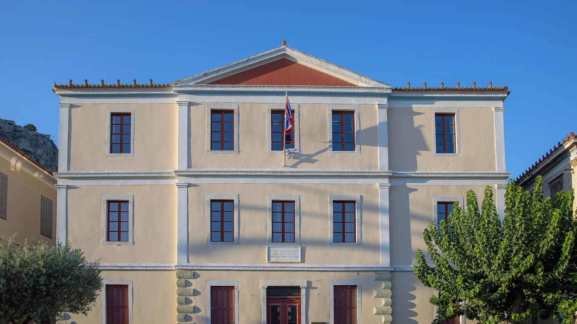 Nafplio Town Hall in the historic centre, with a pale neoclassical facade and red window frames