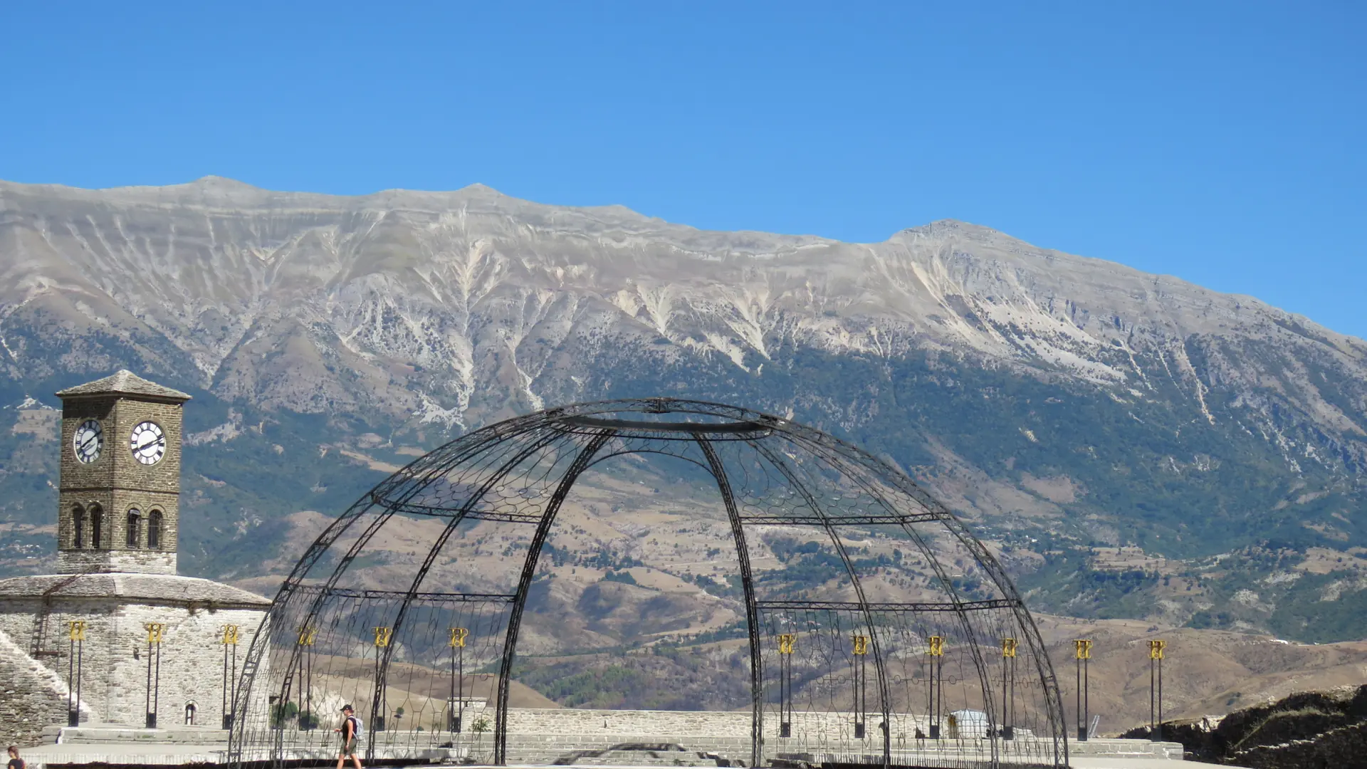 The clock tower and festival stage inside Gjirokastër castle with mountains behind on a clear day
