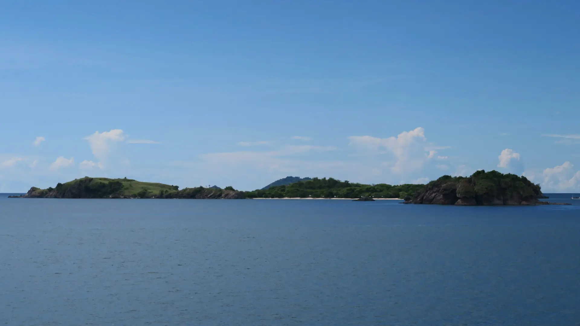 Low green islands and blue water just off Labuan Bajo, a wider coastal view
