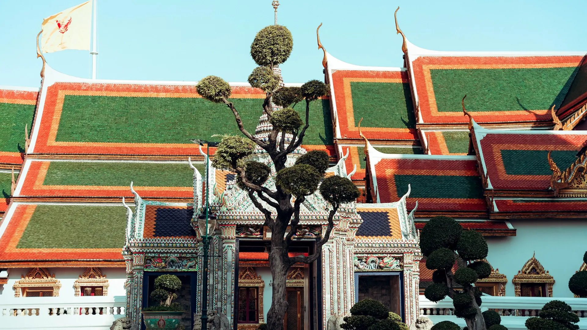 Colourful temple roofs and clipped topiaries at a Bangkok wat