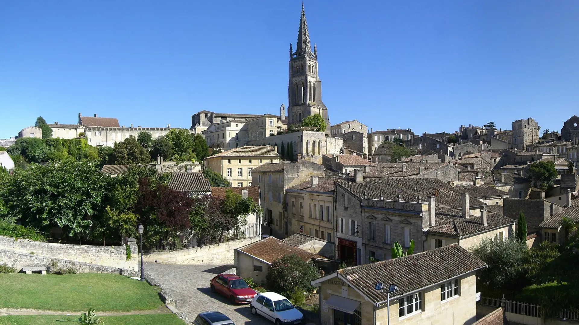 Saint-Émilion’s monolithic church bell tower above sunlit stone houses and tiled rooftops
