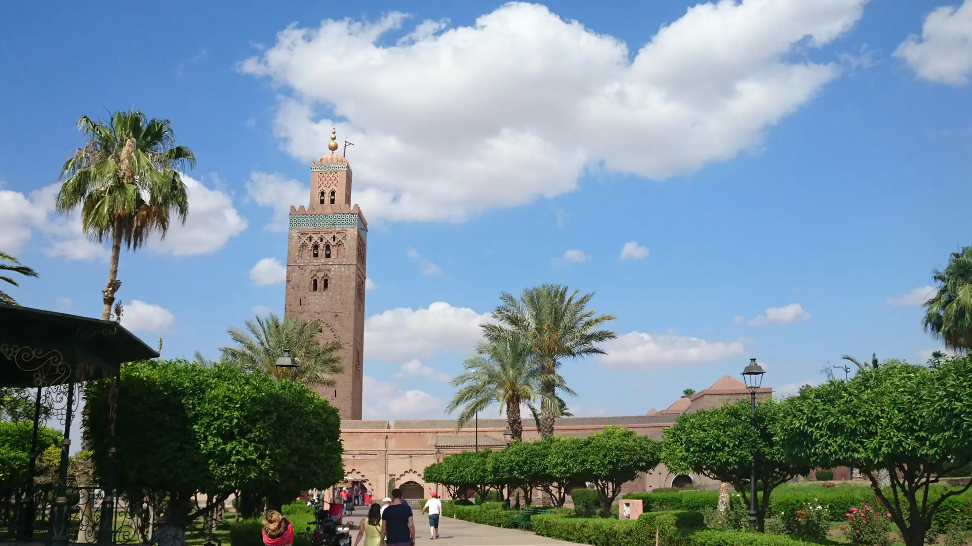 Koutoubia minaret rising above palm gardens in sunlit Marrakech