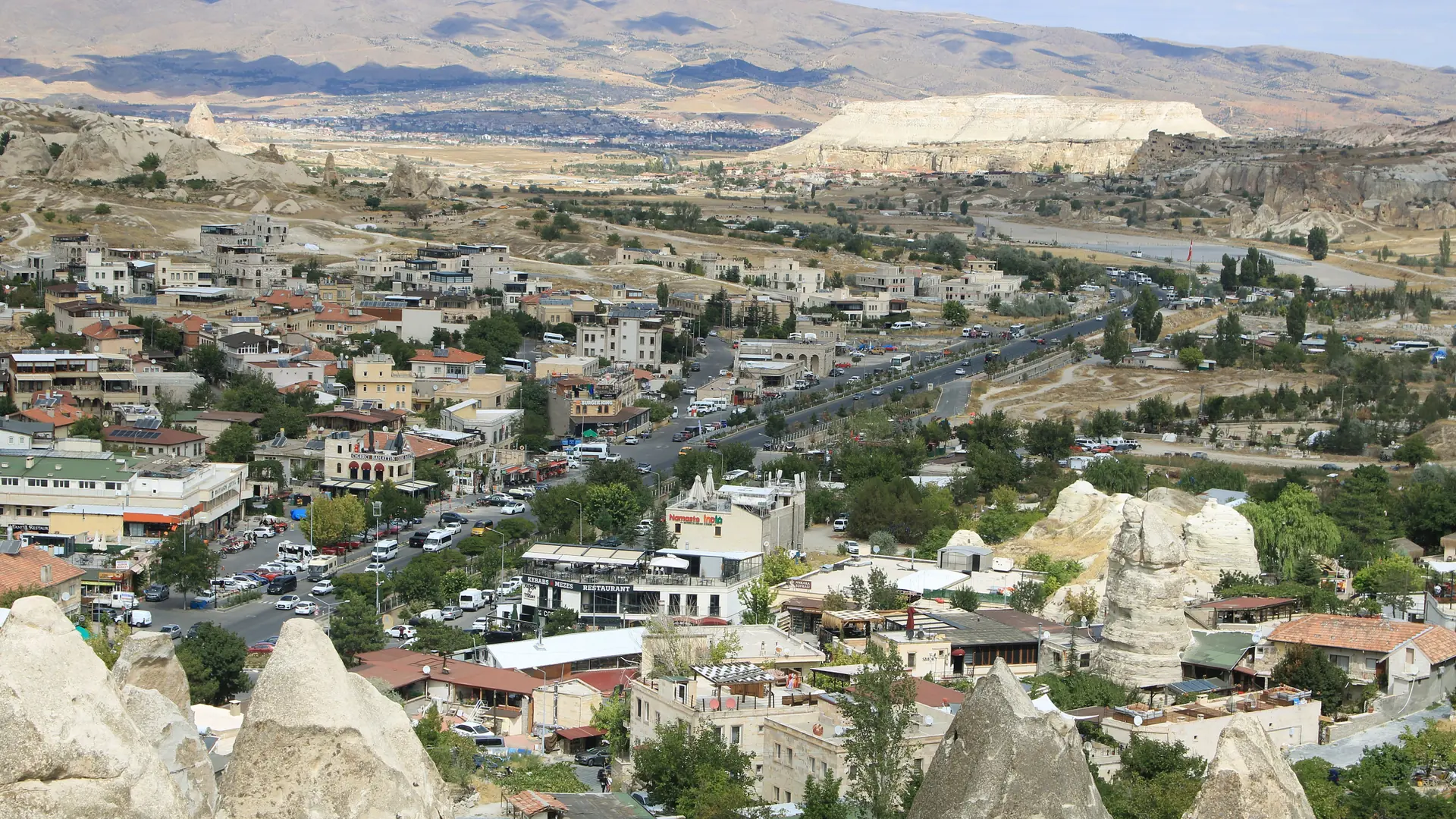 Göreme town and sunlit pale rock hills, shown as a wider Cappadocia scene