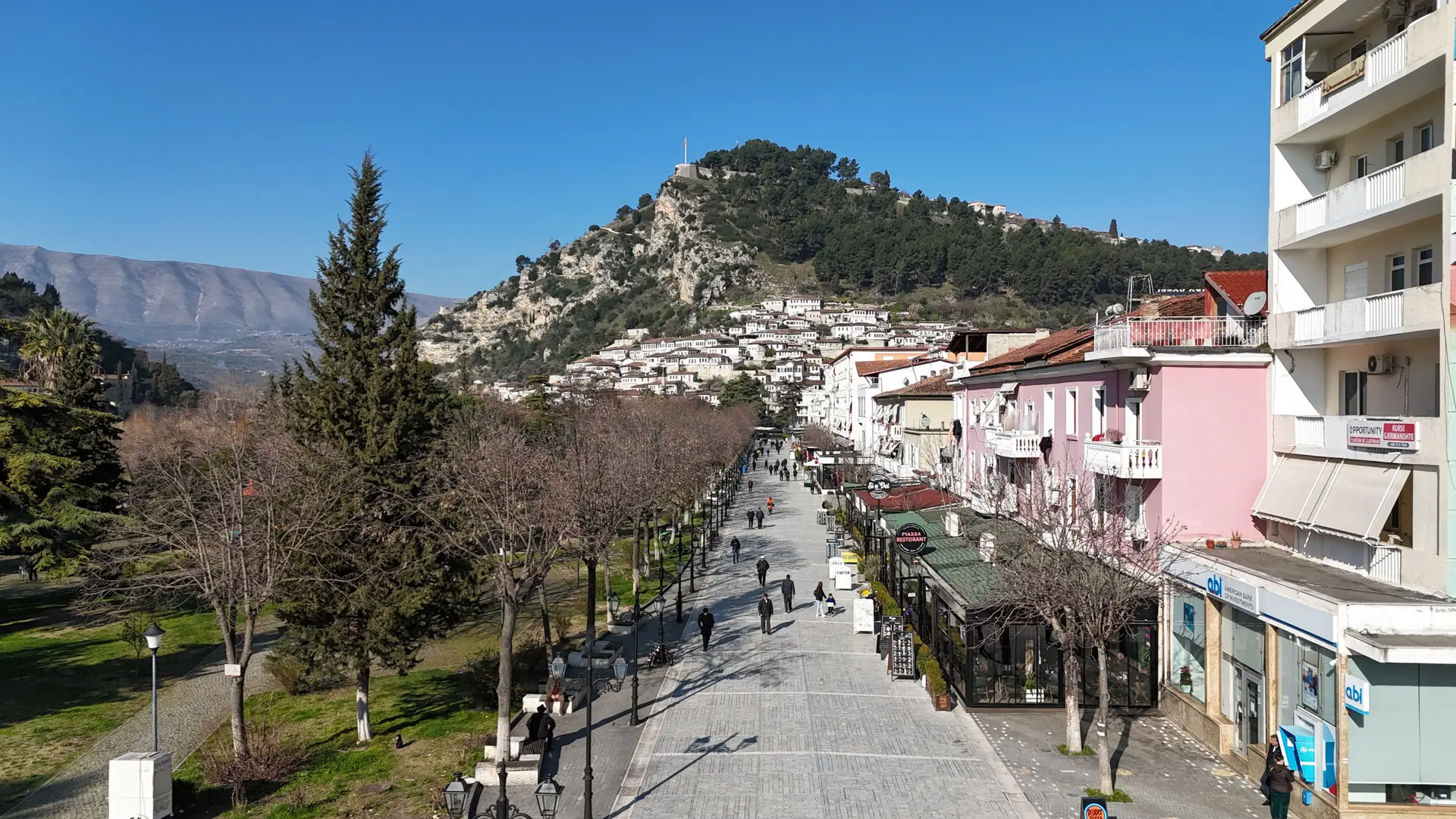 Bulevardi Republika, Berat's tree-lined main street, with the castle hill behind on a sunny day