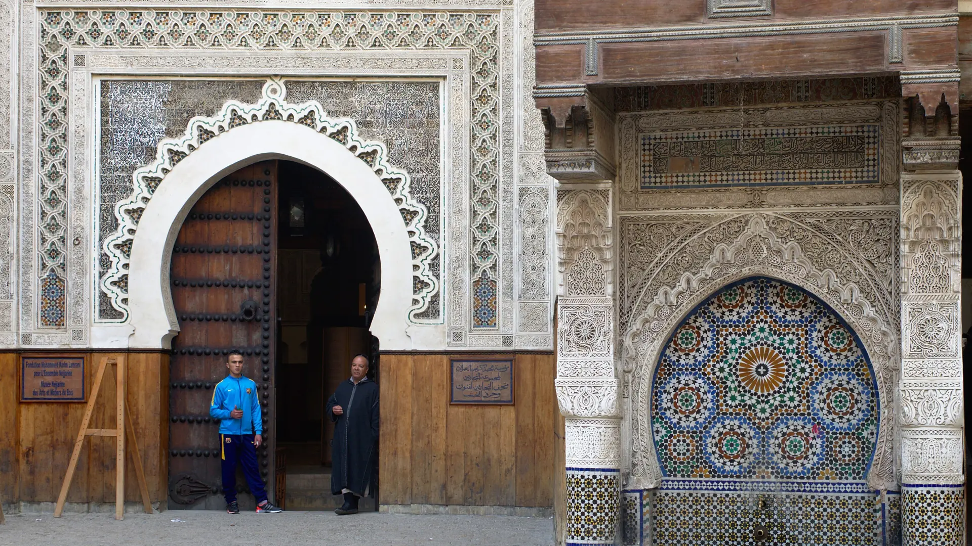 Carved stone fountain and decorated doorway at Nejjarine in Fez