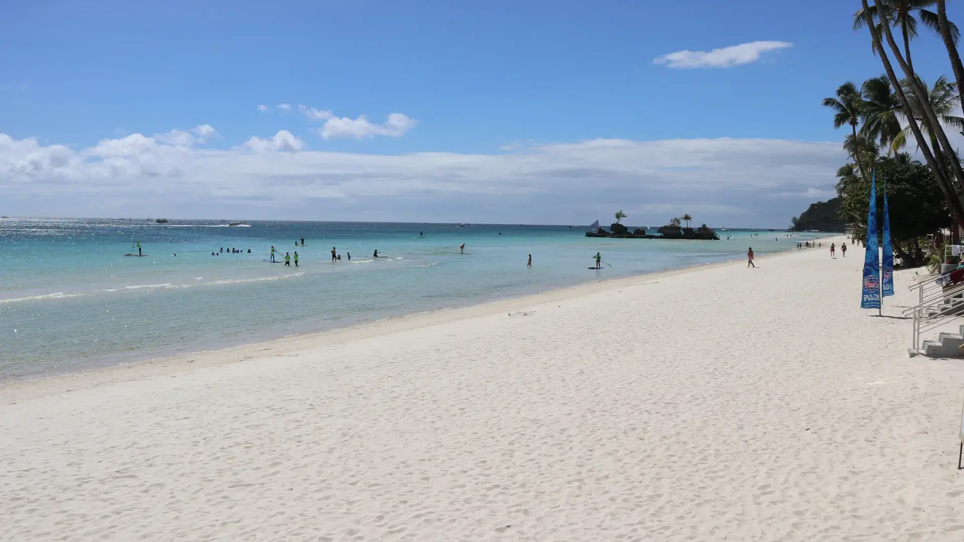 Wide white sand and shallow turquoise water at Station 1, White Beach, with Willy's Rock offshore