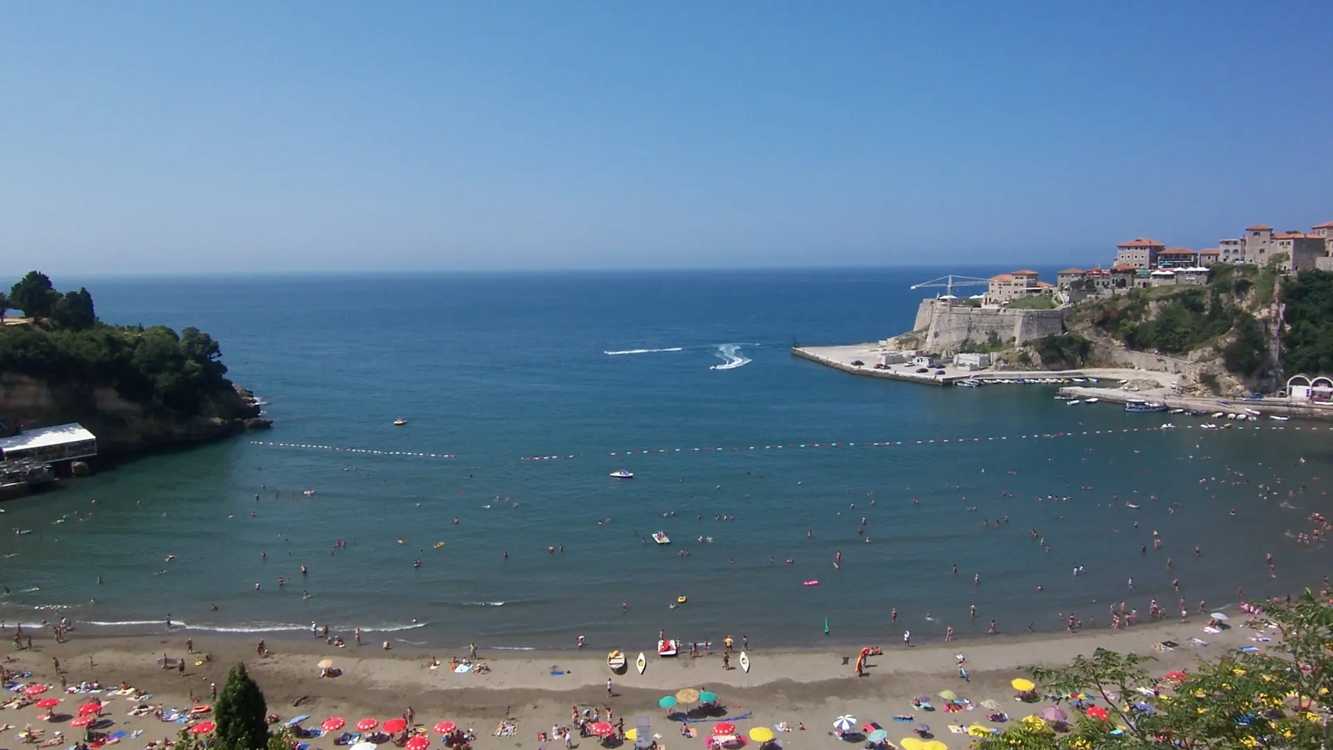 Mala Plaža's sandy arc beneath Ulcinj Old Town beside a blue bay