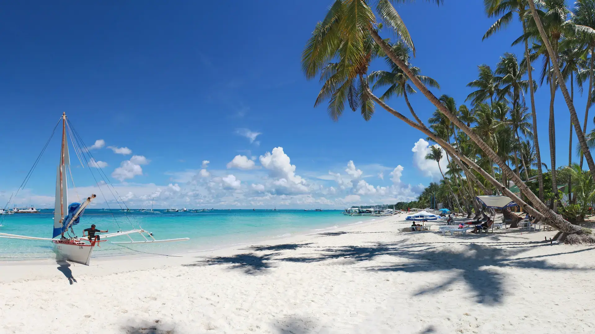 A paraw beside palms, white sand and turquoise water at Station 3 on Boracay’s White Beach