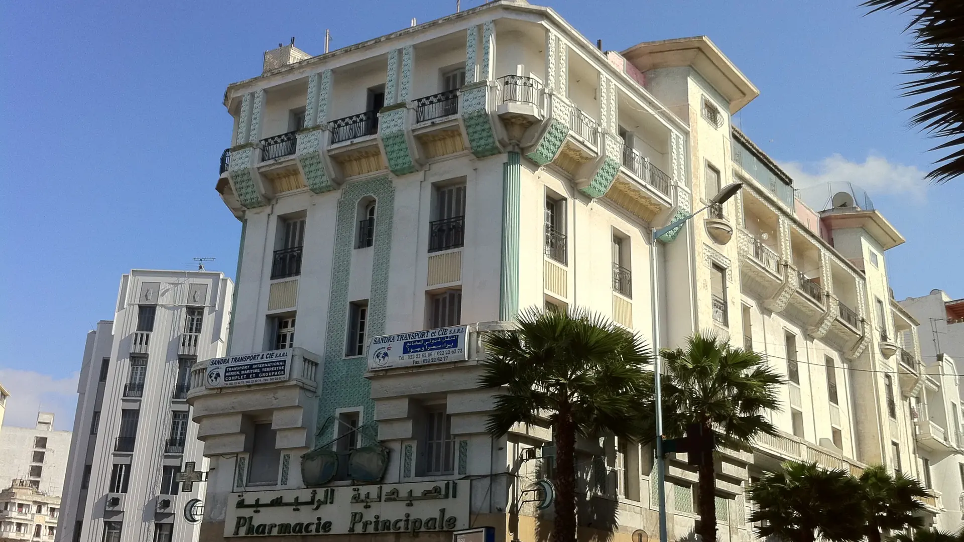 Sunlit Art Deco corner building and palm tree in Casablanca