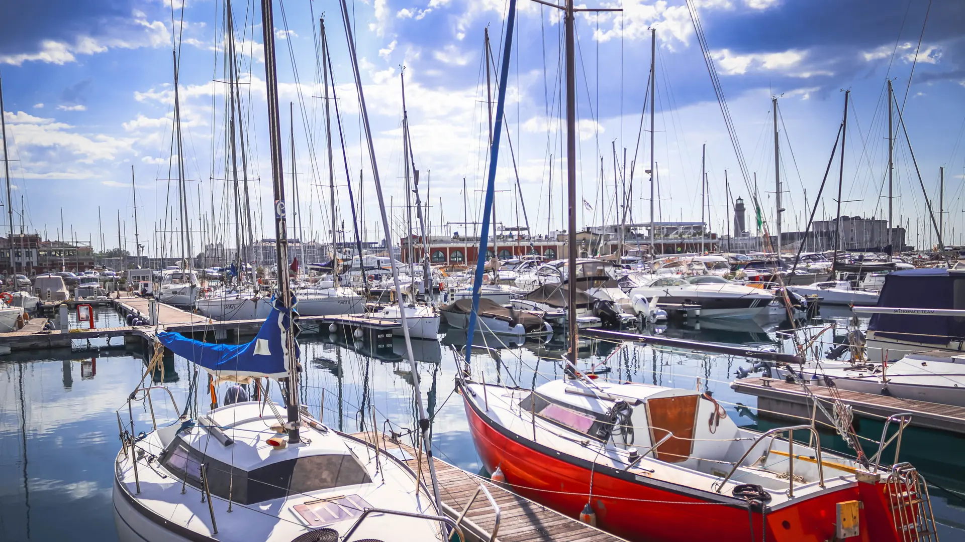 sailboats moored in Lagos marina under a bright blue sky with scattered clouds