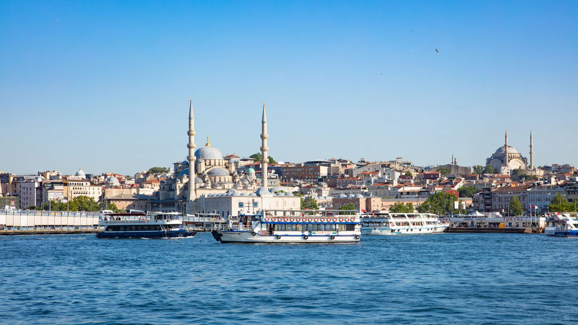 Istanbul mosque domes and minarets above the sunny Bosphorus with blue water and ferries