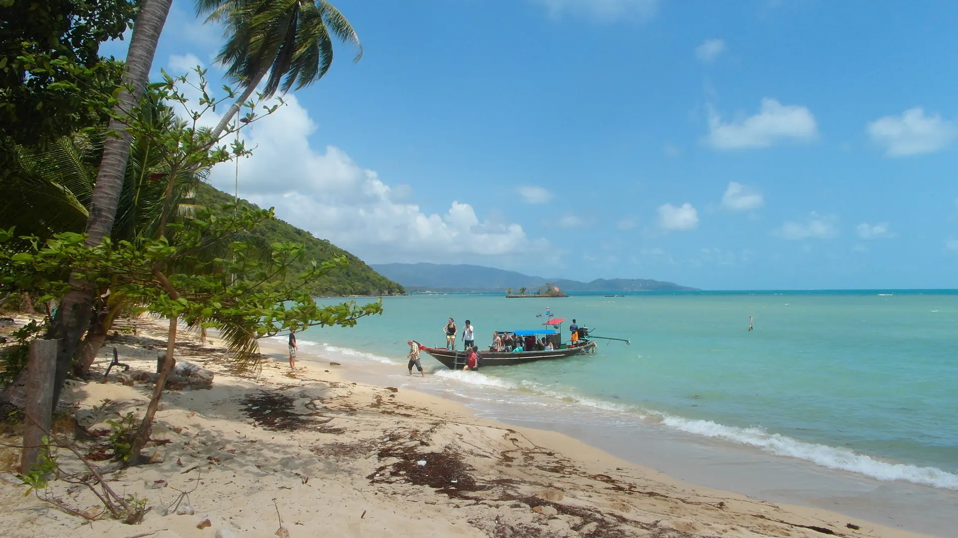 Rocky tropical shore and green hills beside Koh Samui's blue sea