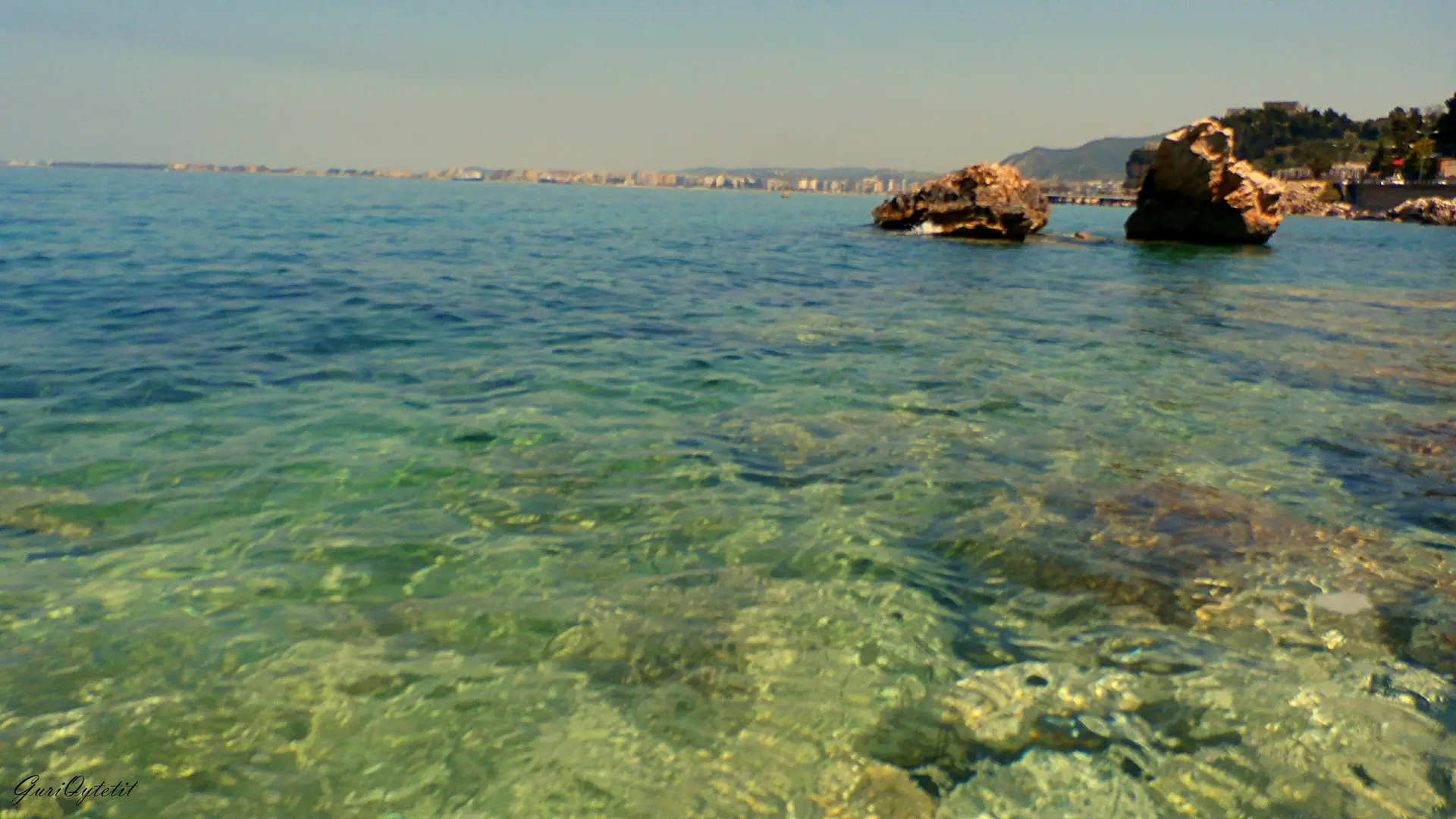 Rocky shoreline and clear water at Uji i Ftohtë on the southern edge of Vlorë on a sunny day