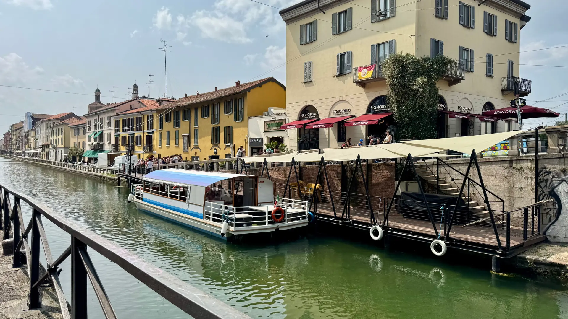 A moored boat on Naviglio Grande beside yellow waterfront buildings in Milan’s Navigli district.