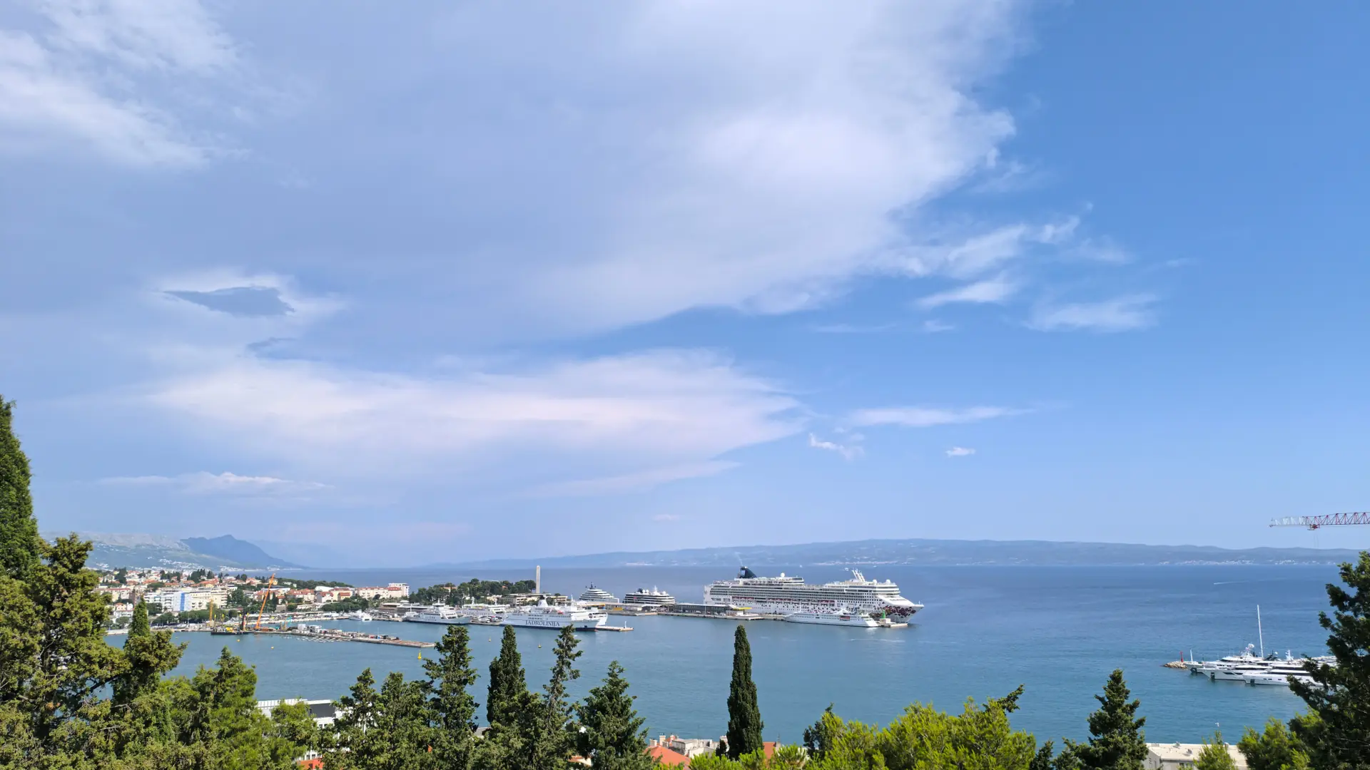 Split harbour, ferries and the Adriatic seen above a wooded coastal hillside