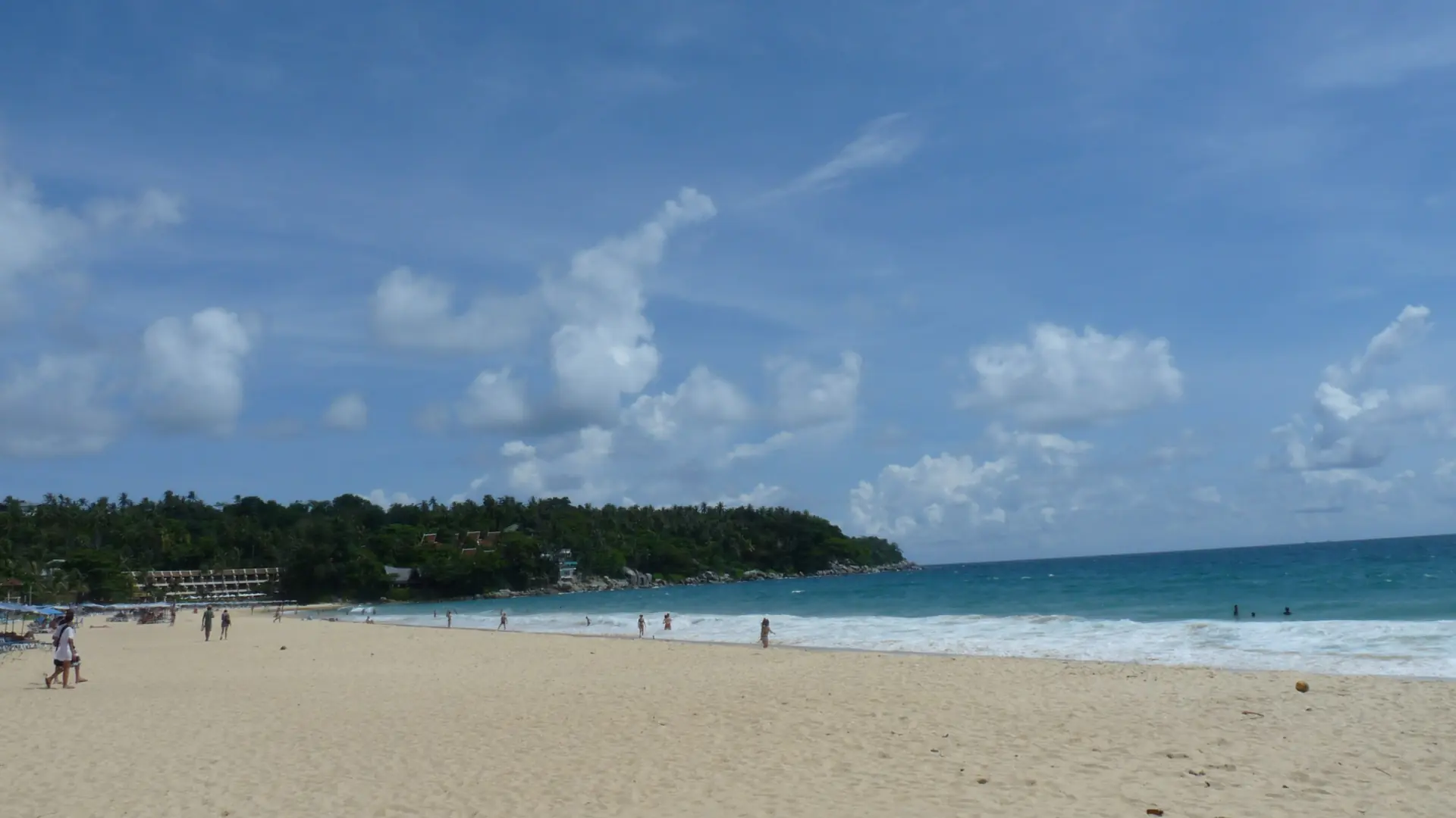 Daylight sand, surf and a green headland at Karon Beach on Phuket