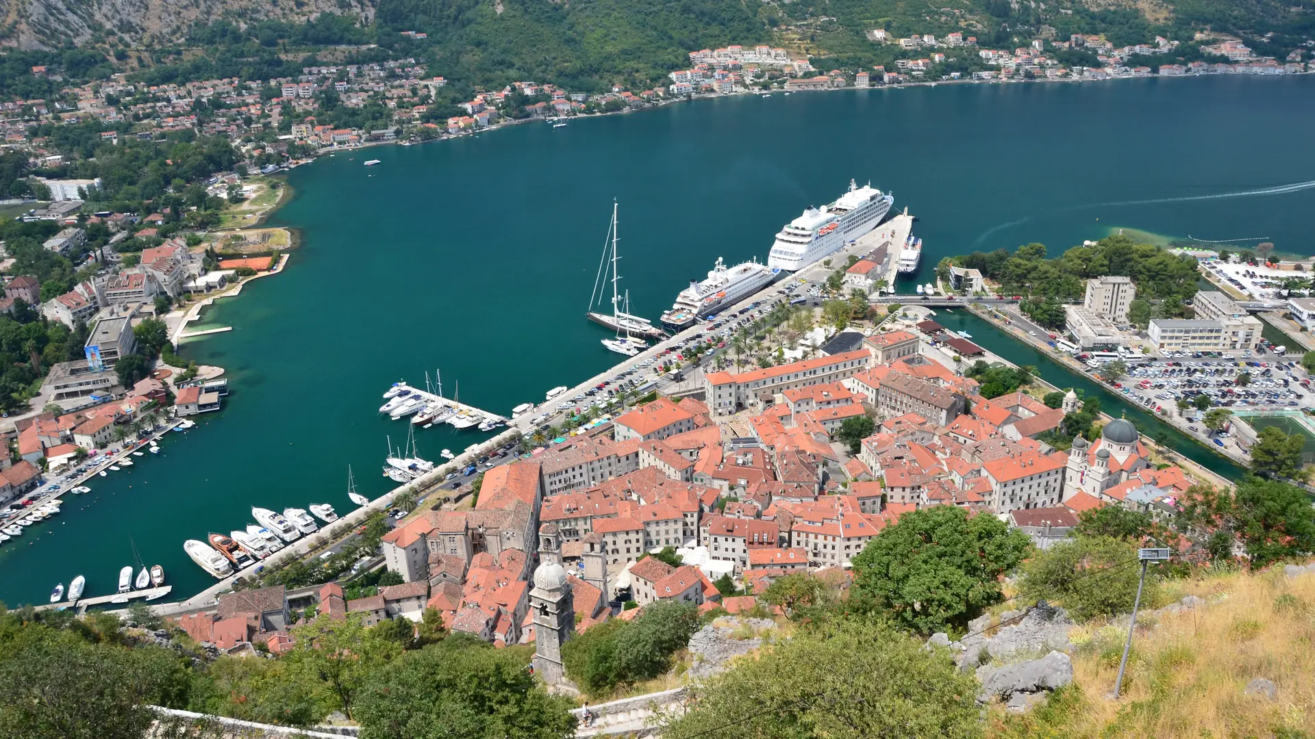 Kotor Old Town beside the inner bay and mountain walls in bright daylight