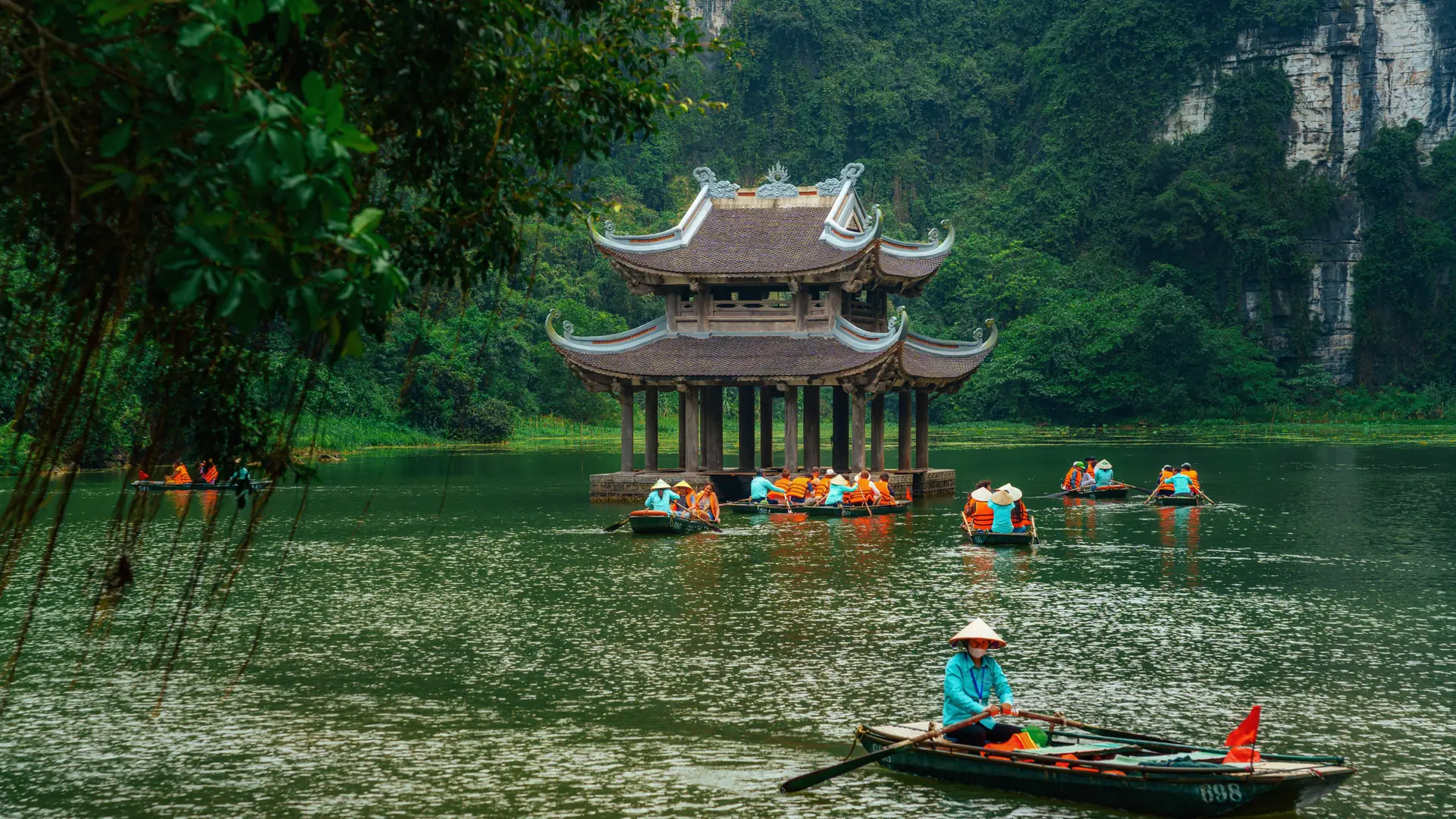 Rowboats passing the three-roof Thuy Dinh pavilion in the Trang An landscape