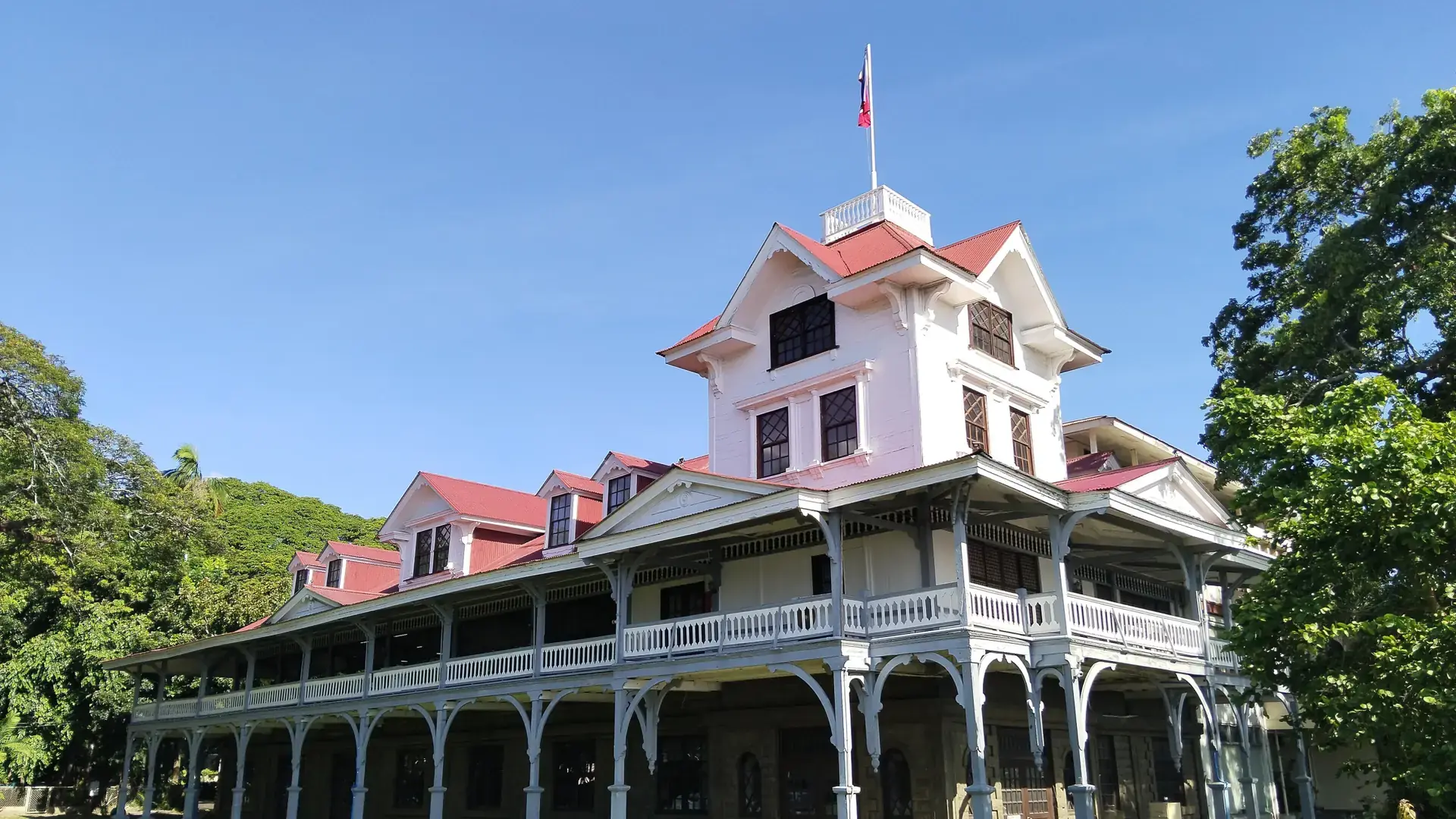 Silliman Hall’s white timber verandas and red roofs beneath a blue Dumaguete sky