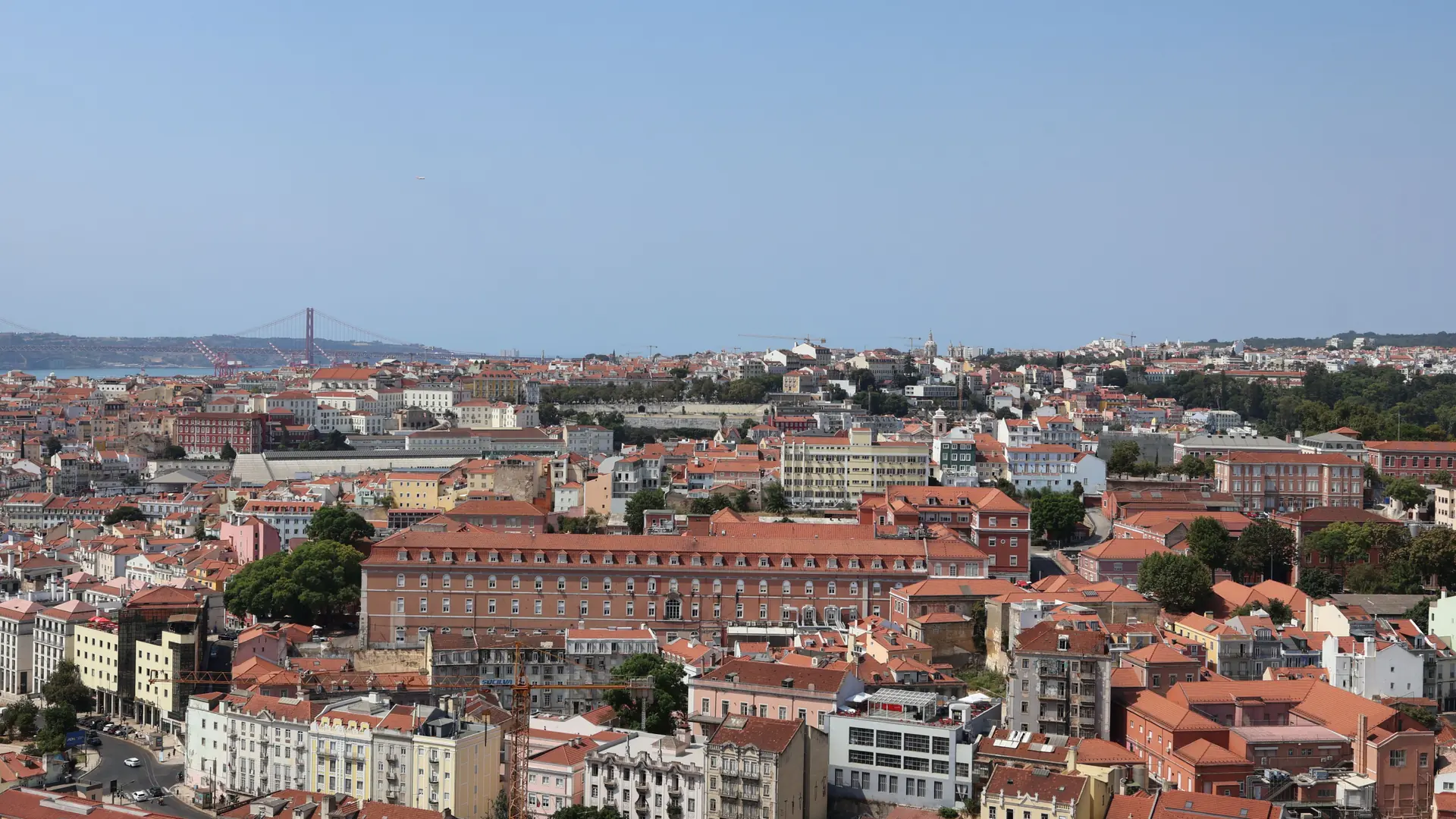 Bright view across Lisbon's red roofs, tiled façades and the Tagus river