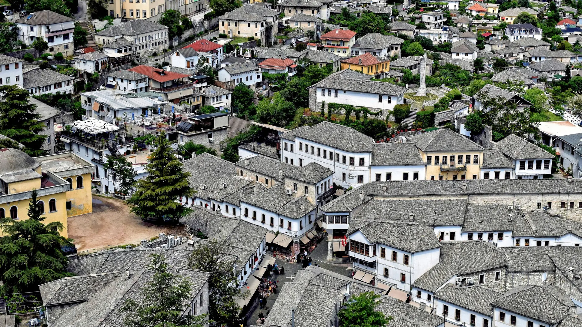 Slate roofs and white stone houses of Gjirokastër's old town spreading down the slope on a clear day