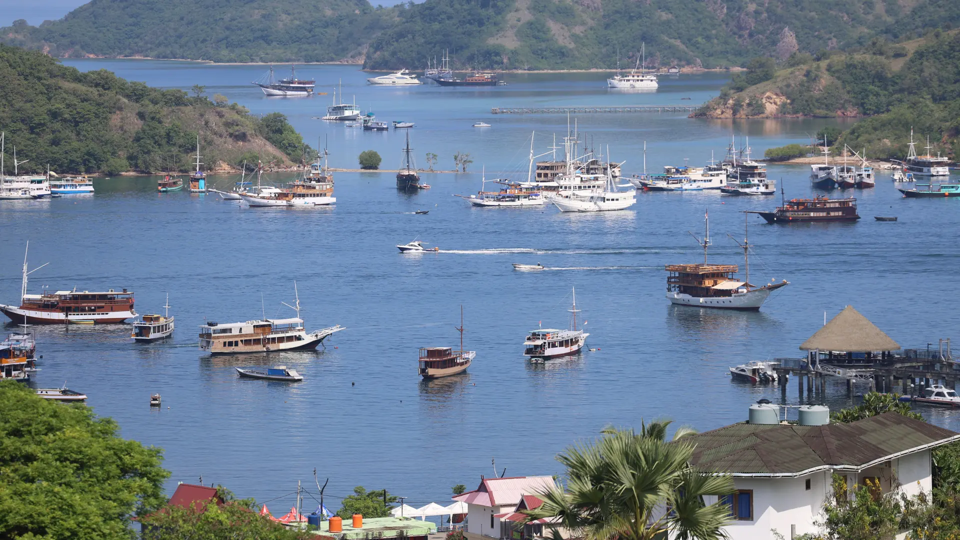 Tour boats anchored in Labuan Bajo’s blue bay between green hills