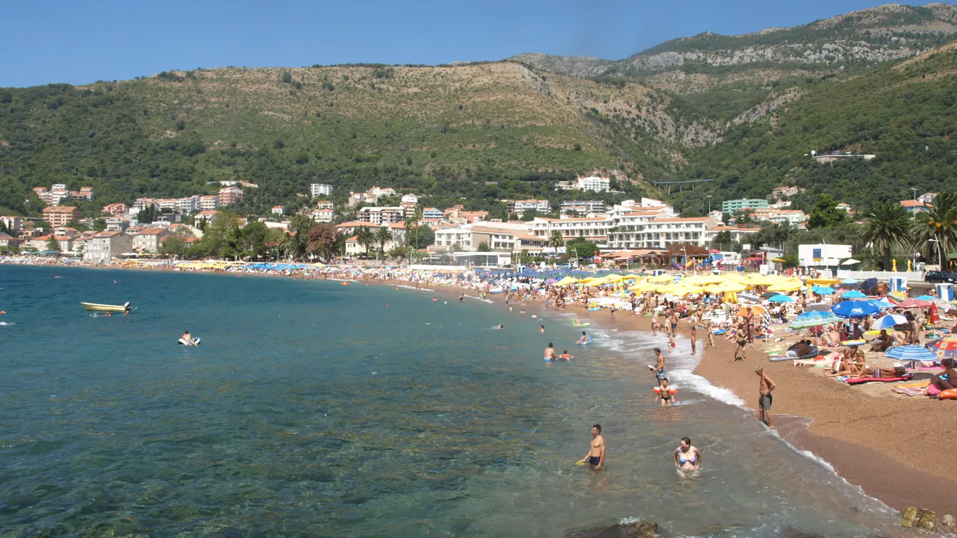 Petrovac town beach beneath green hills in clear daylight