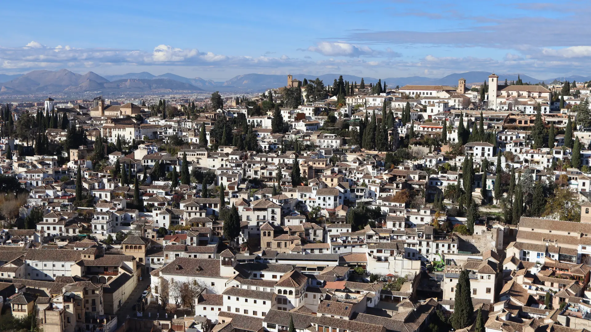 White houses and the San Nicolás church across Granada’s Albaicín hillside in daylight