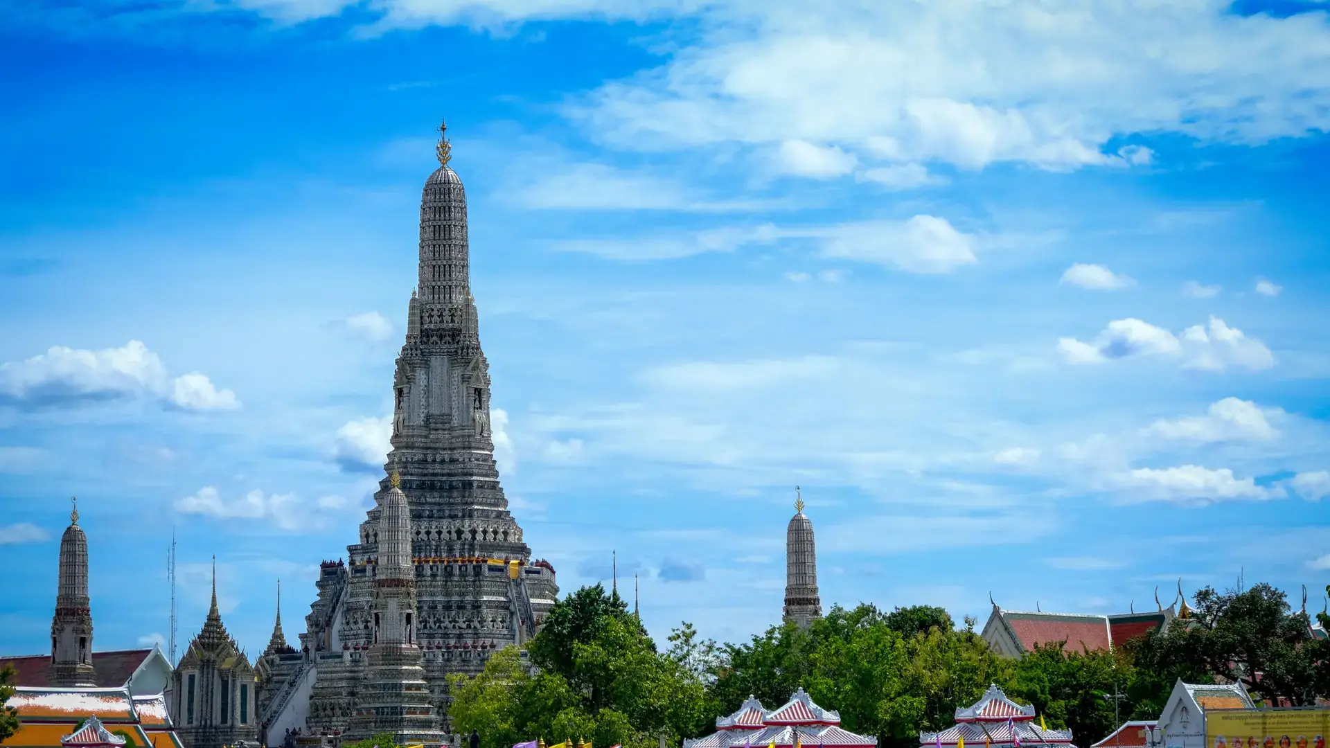 Wat Arun's decorated spires rising above Bangkok's riverside in clear daylight