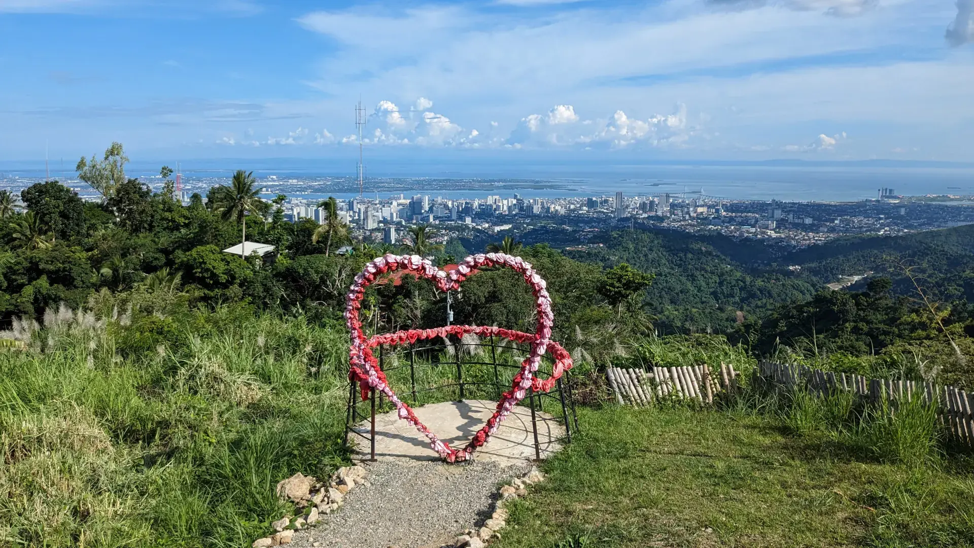 A heart-shaped frame on a Busay hillside overlooking Cebu City and the sea