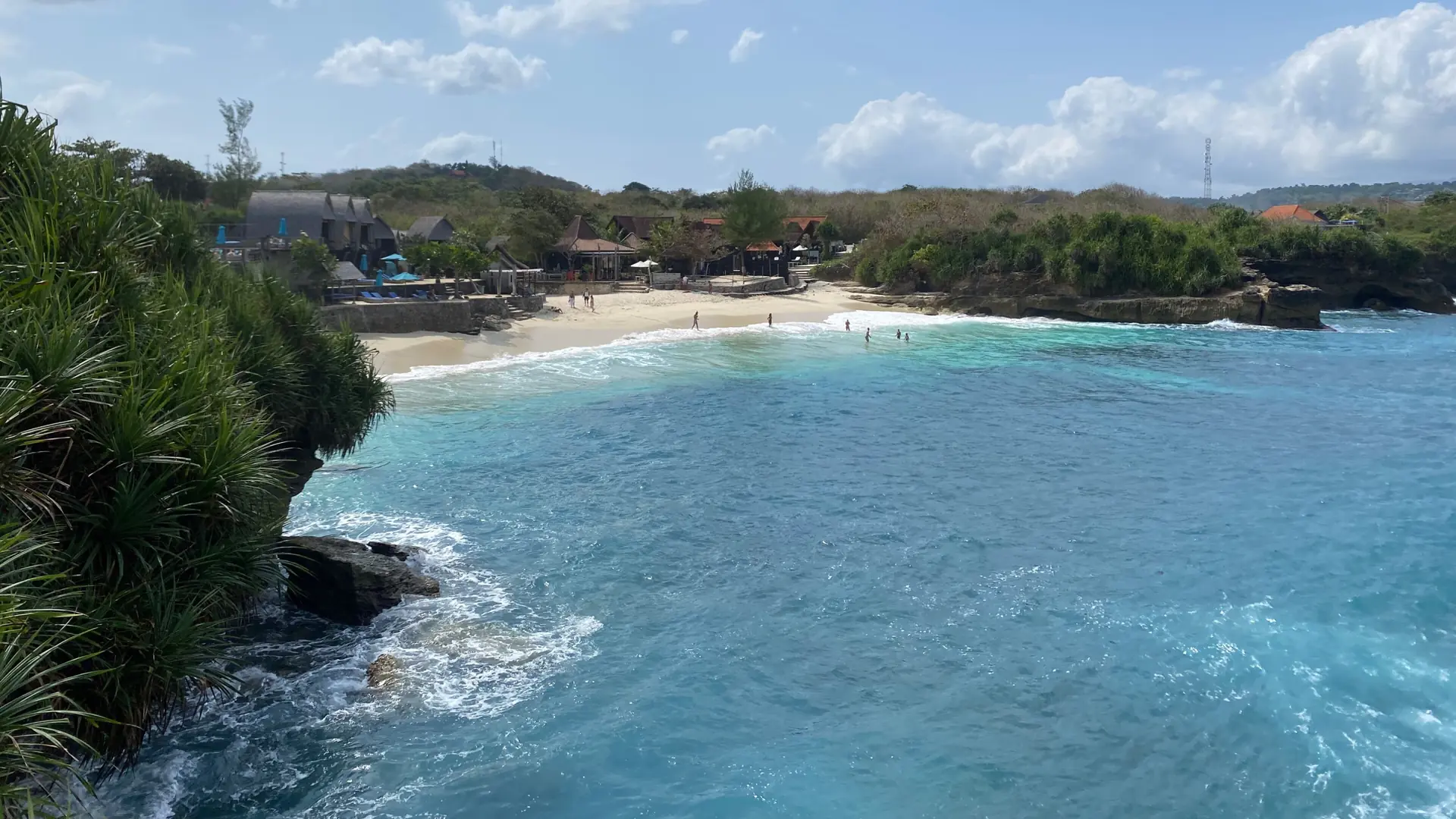 White surf reaching Dream Beach on southern Nusa Lembongan between green coastal headlands