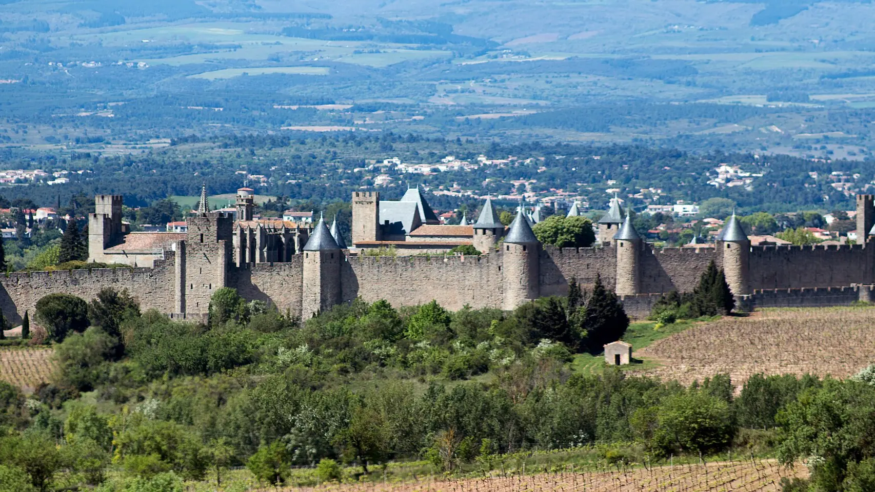 Fortified walls and towers of Carcassonne surrounded by green countryside