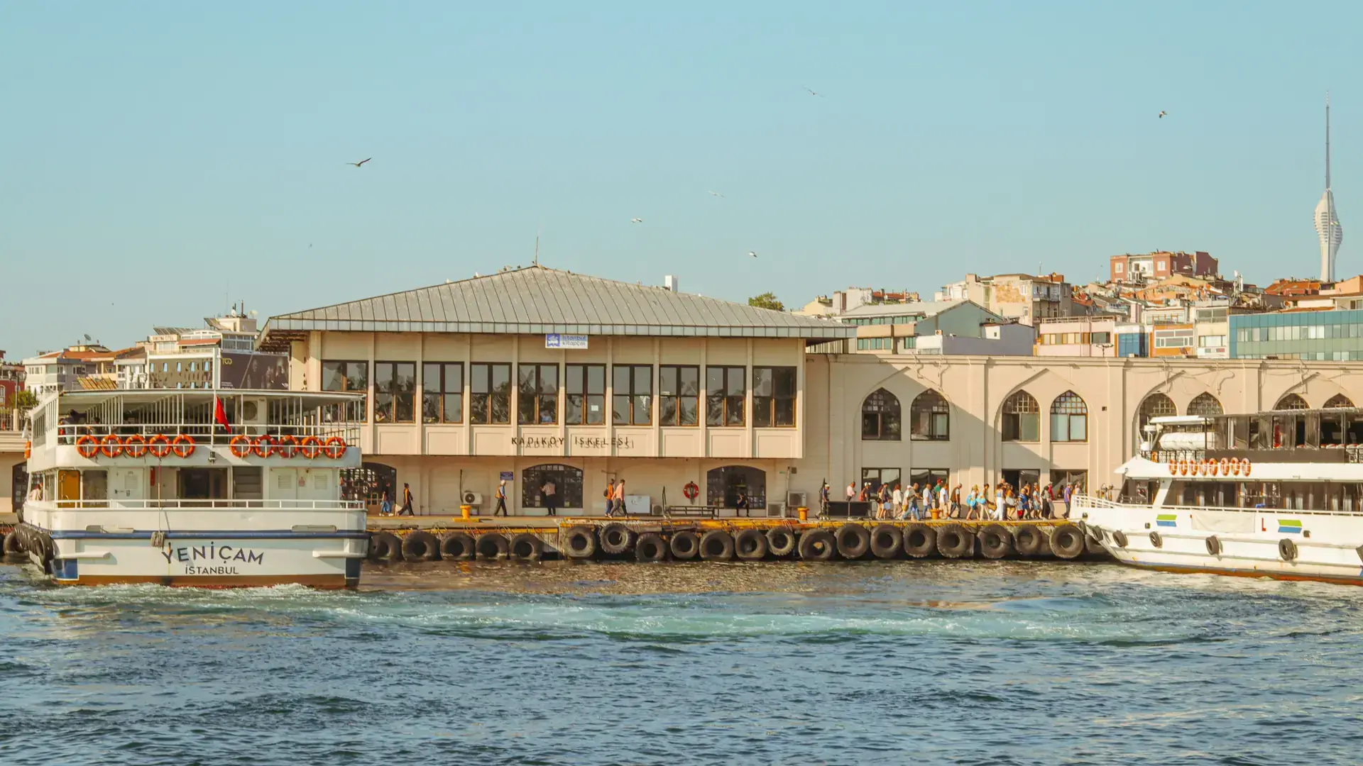 Sunny Kadikoy waterfront with ferries crossing the blue Bosphorus toward Istanbul minarets