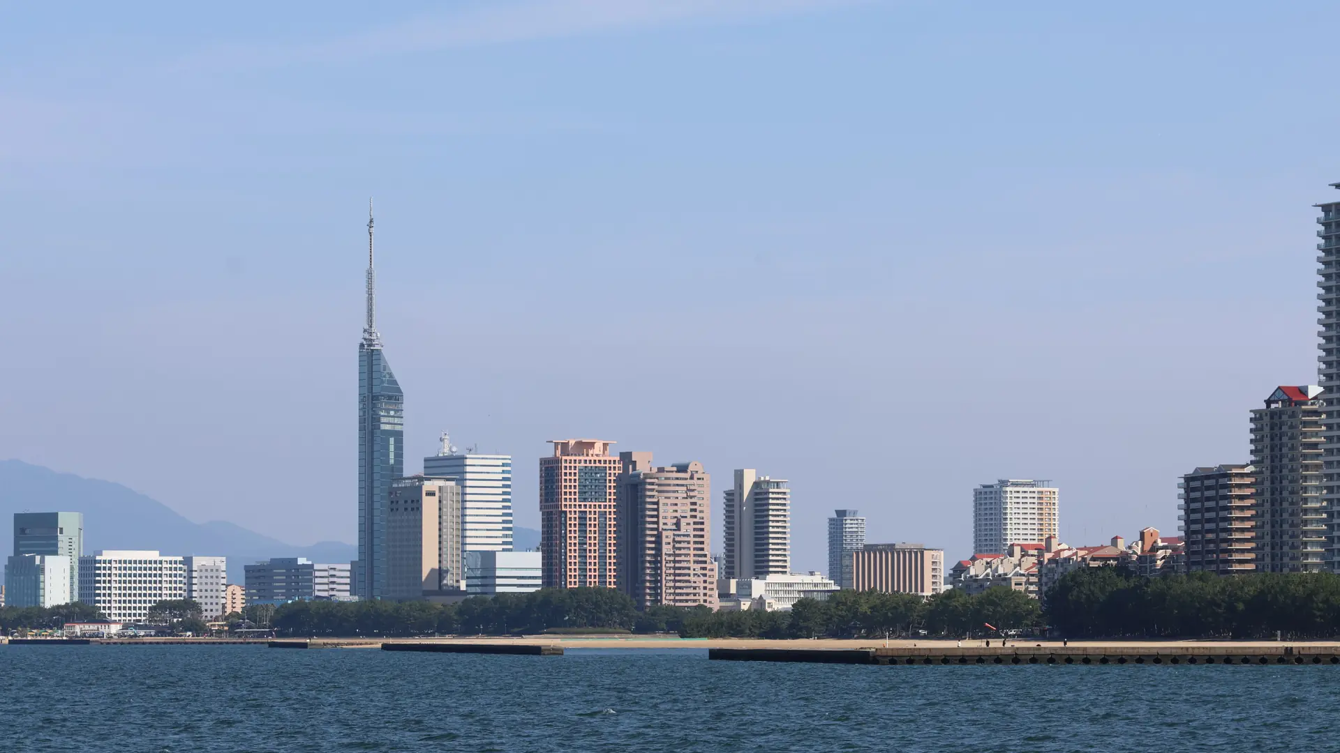 Fukuoka Tower and Momochi waterfront buildings across blue Hakata Bay in daylight