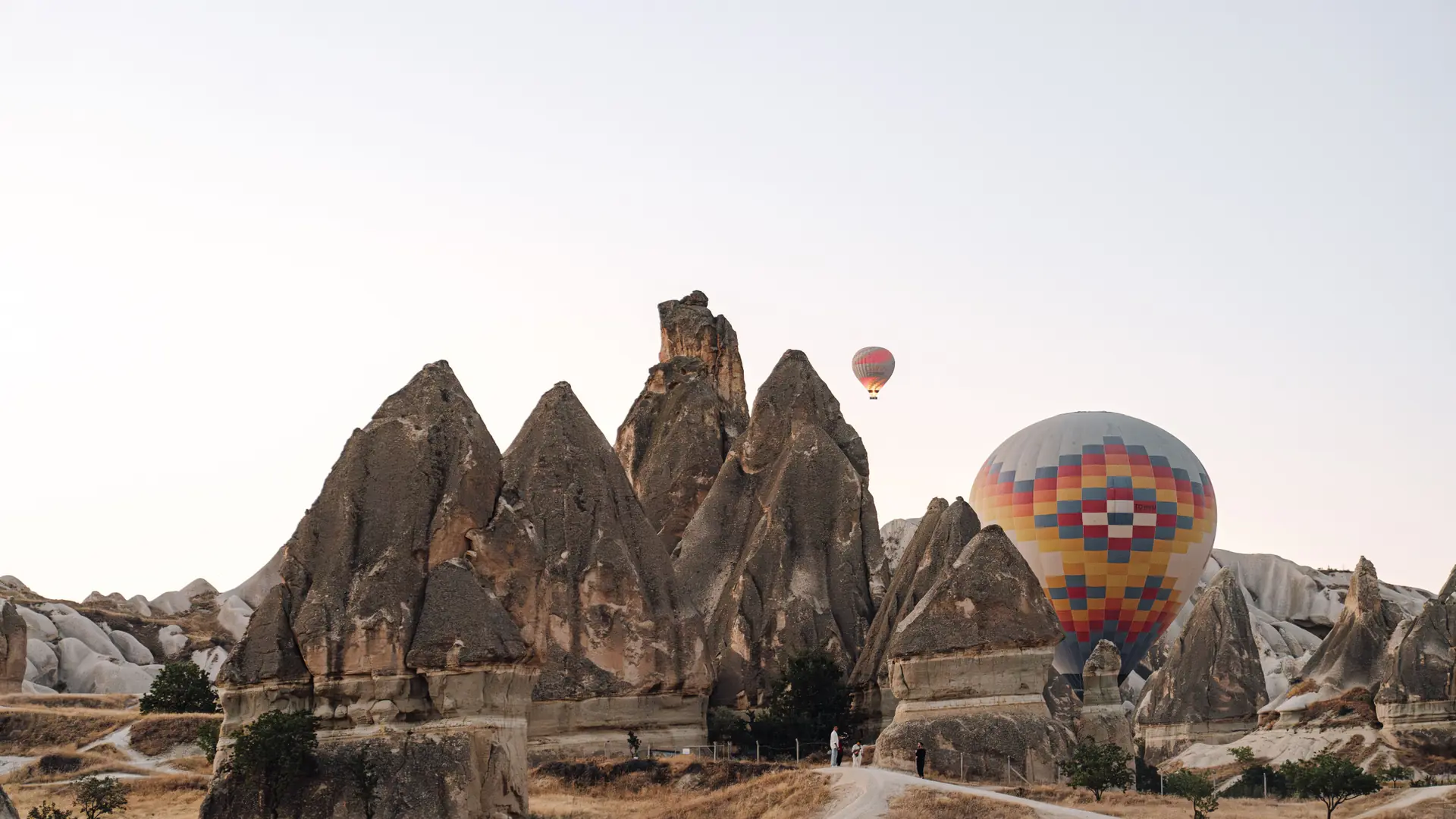 Balloons over Göreme fairy chimneys and golden Cappadocia valleys at sunrise