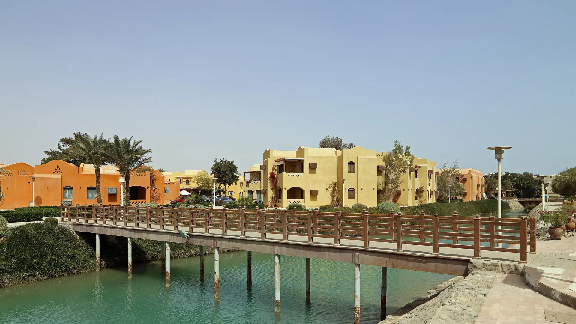 Bridge over a lagoon in El Gouna Downtown, with yellow buildings and palms