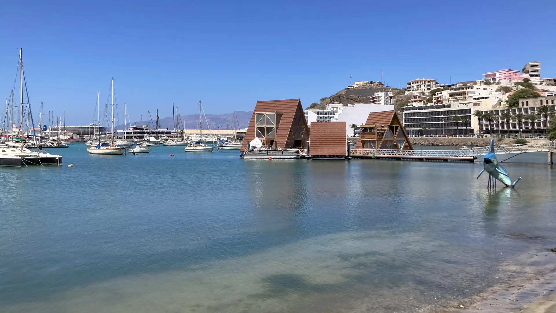 Sunny Porto Grande waterfront in Mindelo, with the Mansa Floating Hub and yachts across the blue bay