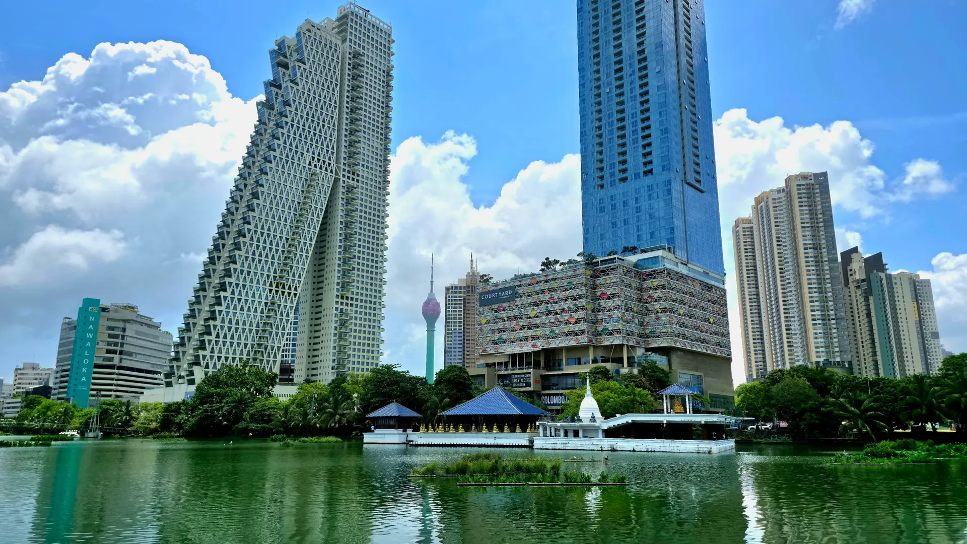 Sunny Colombo skyline reflected in a lake beneath blue sky