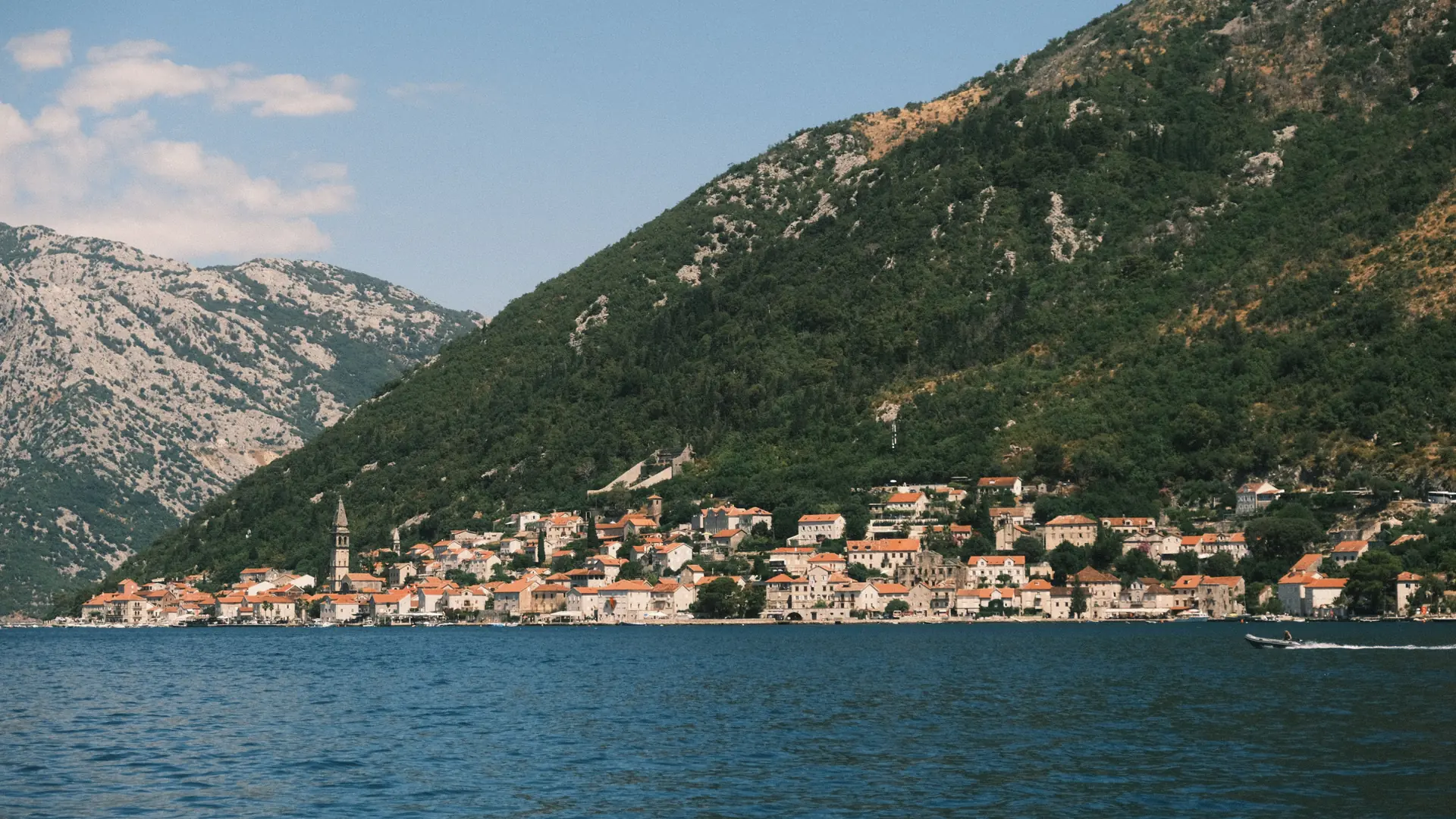 Perast's stone waterfront beneath mountains beside the blue Bay of Kotor