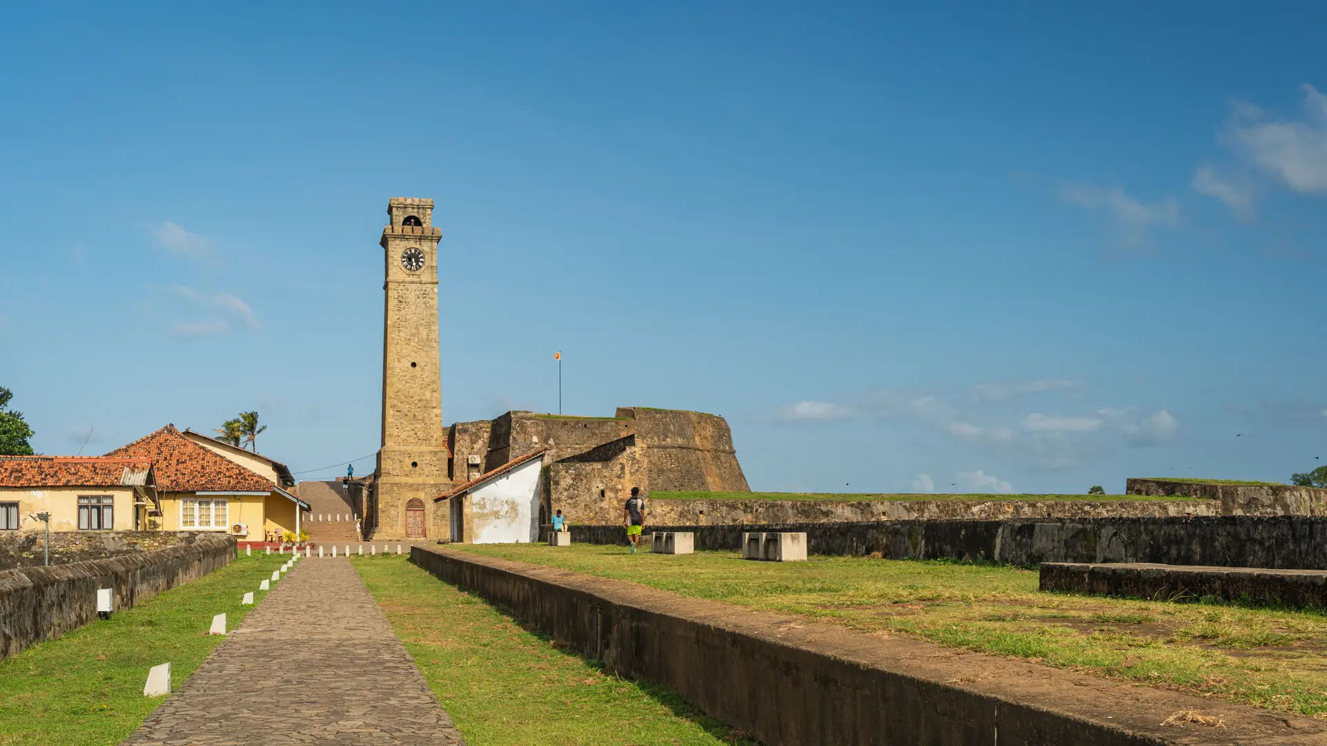 Galle Fort Clock Tower above a grassy stone rampart in clear daylight