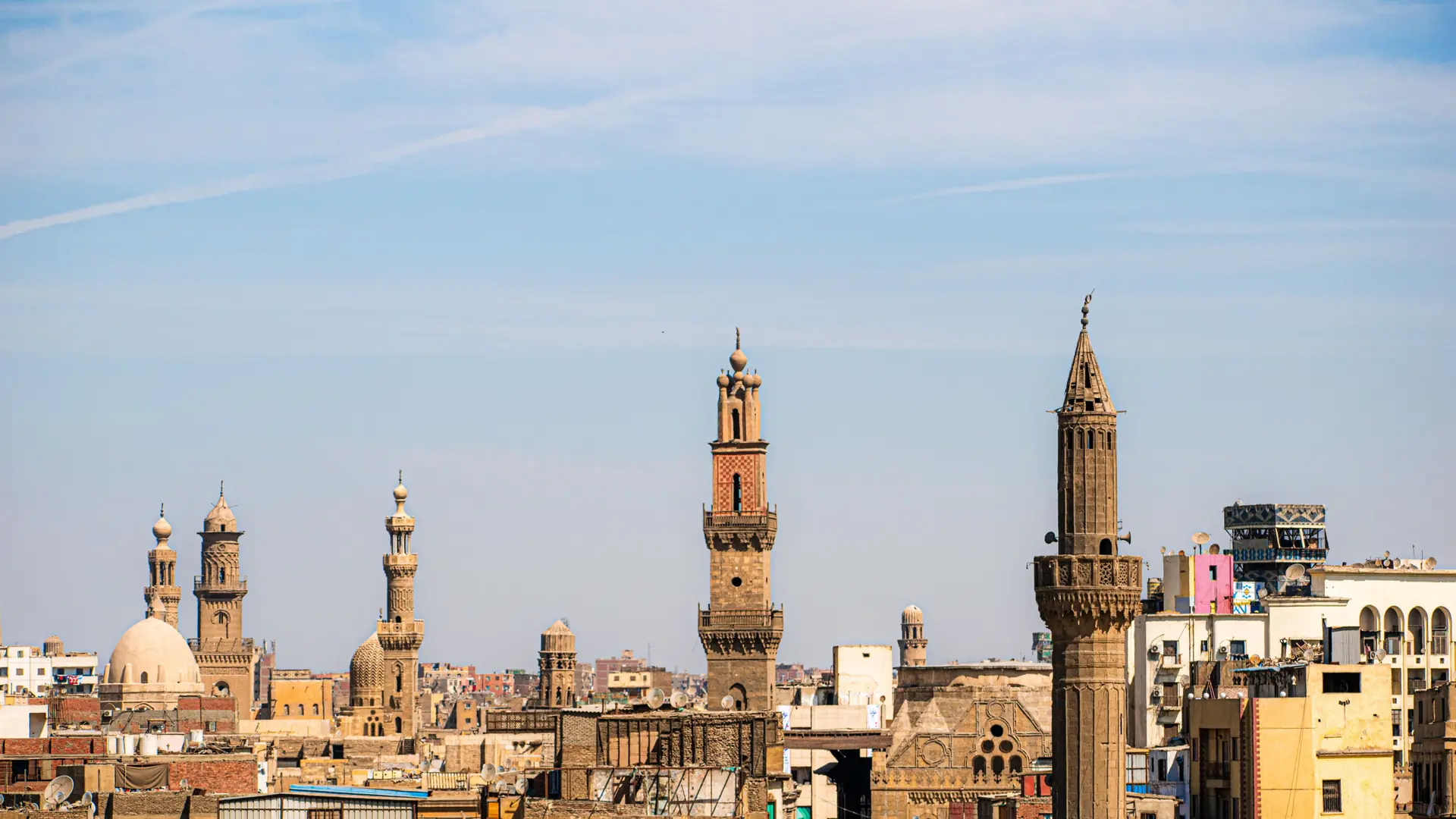 Sunlit historic mosque towers against the clear Cairo sky