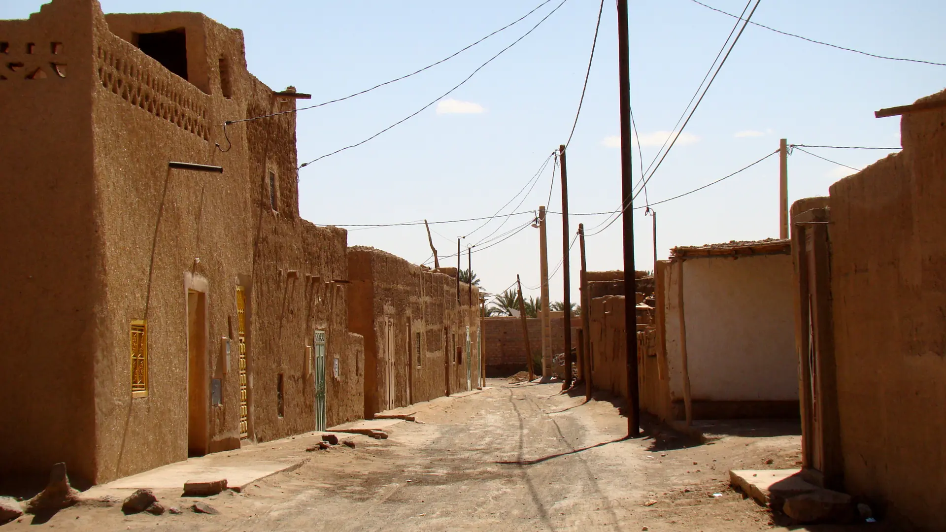 Sunlit mudbrick street in the older part of Merzouga village