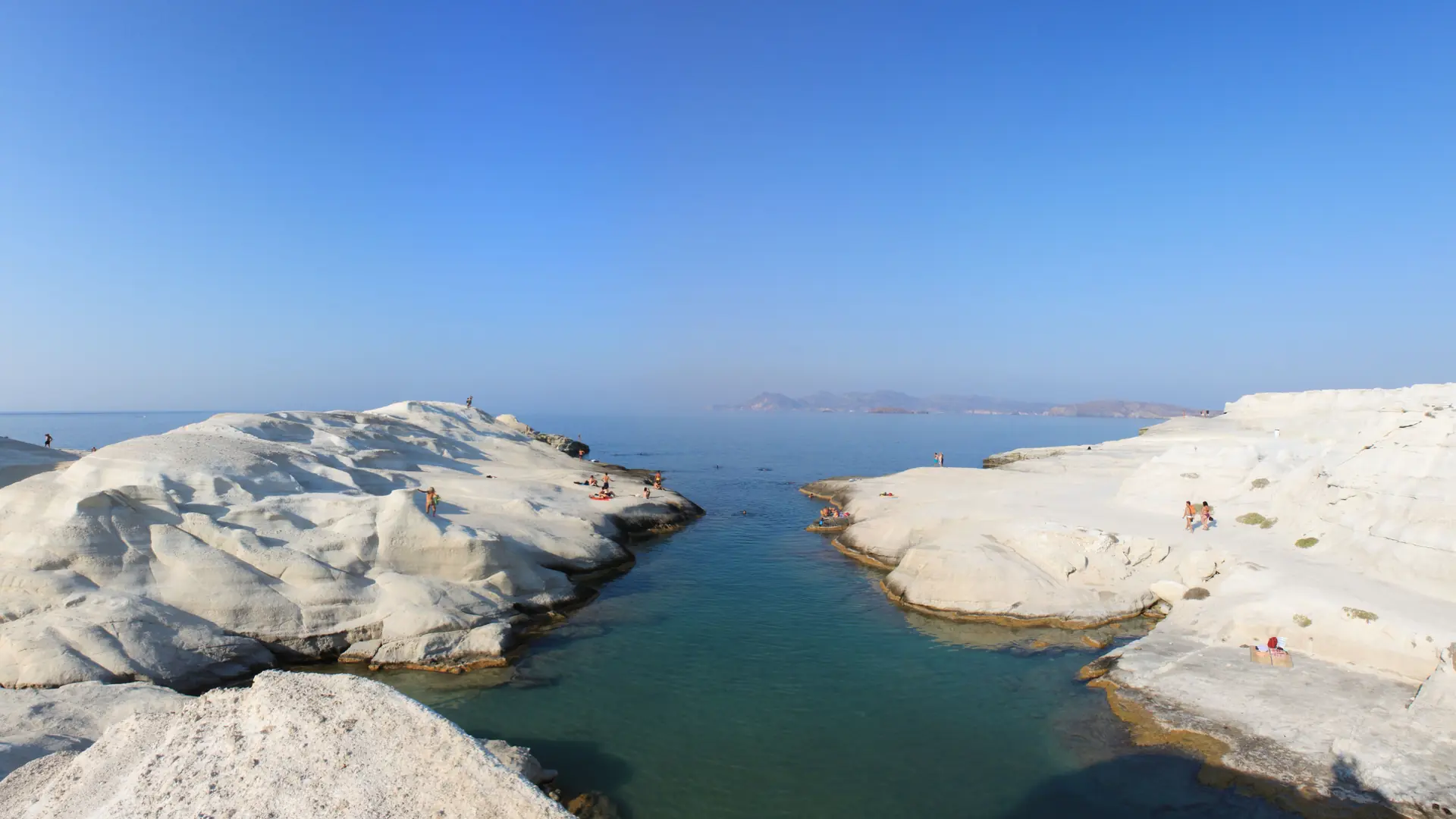White volcanic shelves enclosing clear blue water at Sarakiniko Beach on Milos